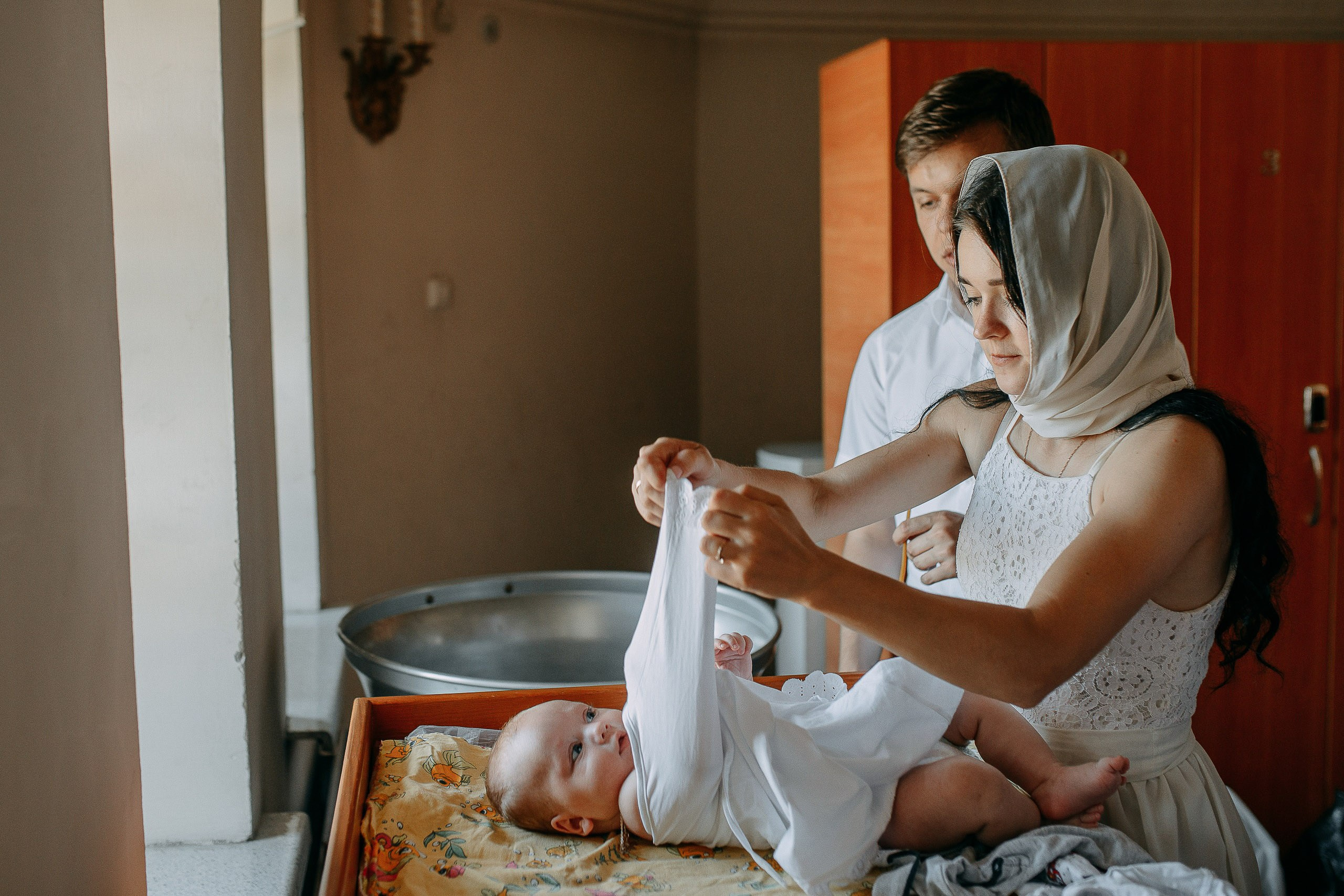 Услуги фотографа на крещение в Новосибирске, подготовка младенца к таинству, облачение в белую рубашку.