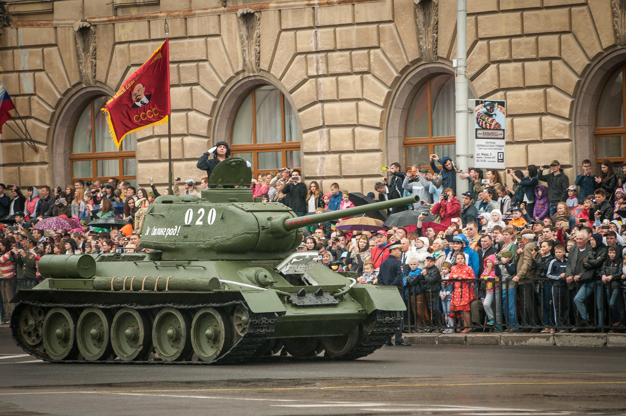 Танк Т-34 едет по Площади Павших борцов на параде вдоль зрителей на улице