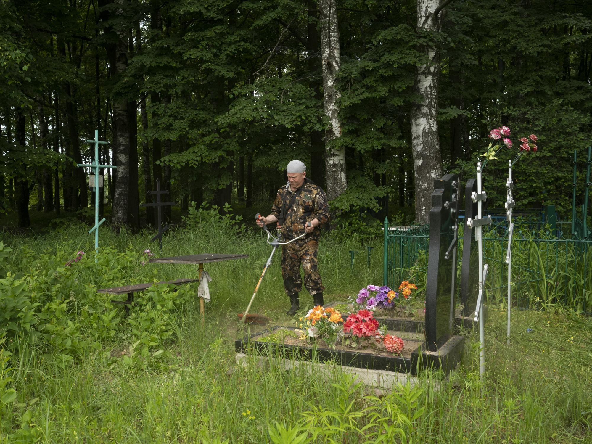 June 10, 2021, Victor, a resident of the city of Novozybkov, mows grass at the grave of his parents in the cemetery in the village of Svyatsk.
