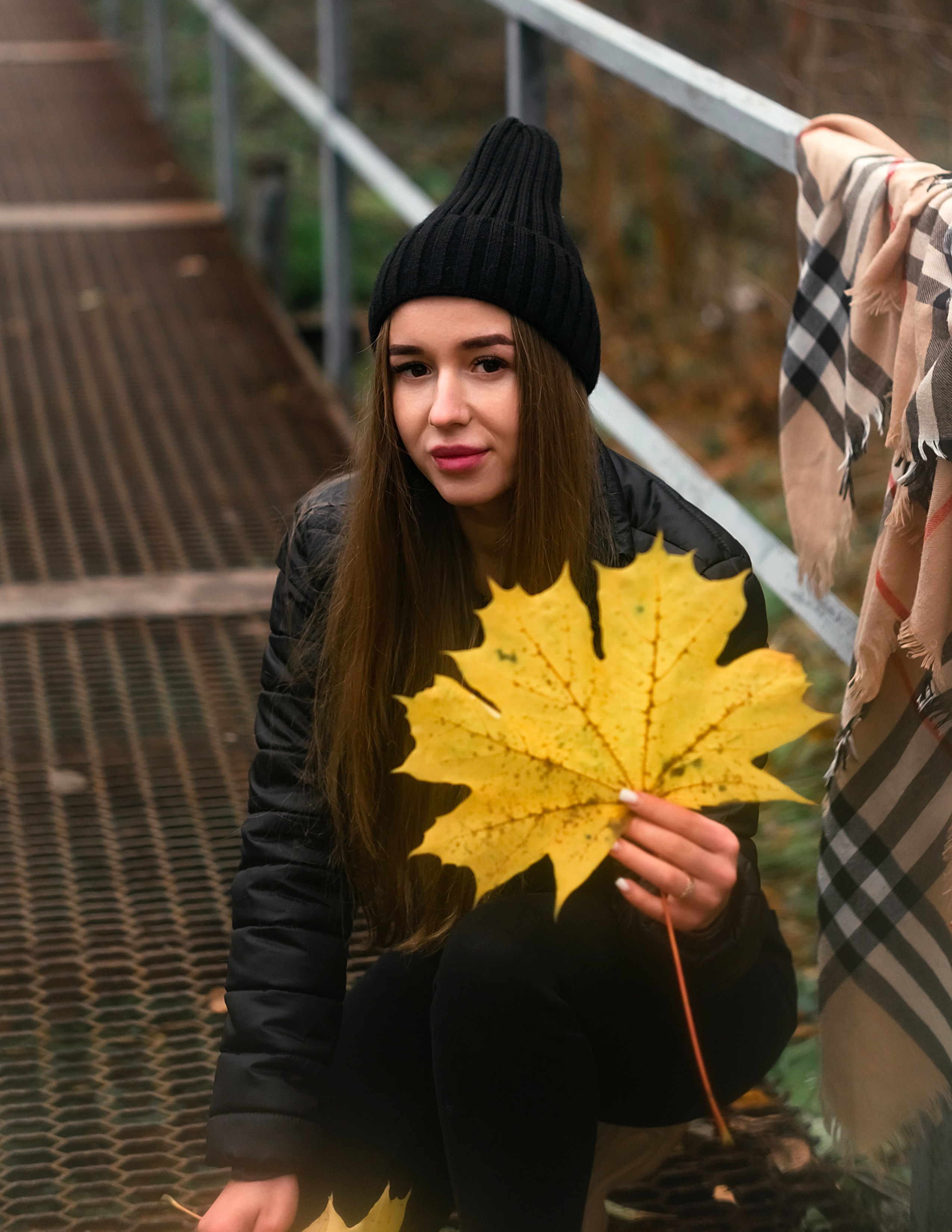 На фото девушка на мостике с осенними листьями.