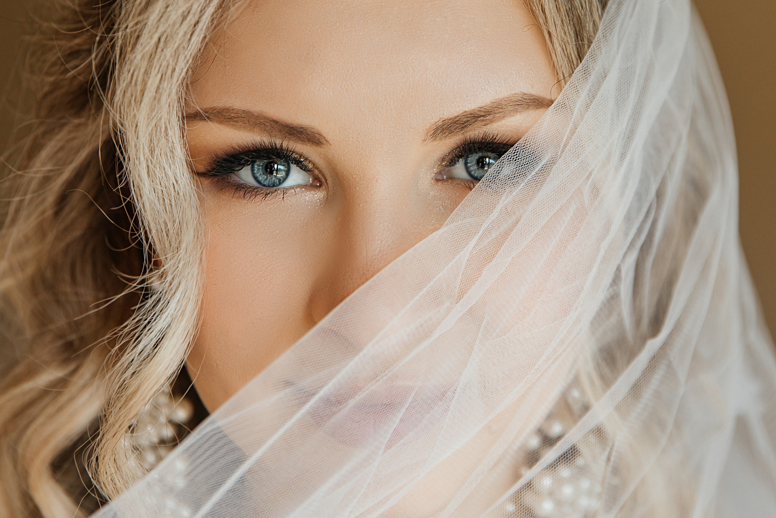 Утро невесты. Девушка с красивыми глазам немного прикрывает свое лицо фатой