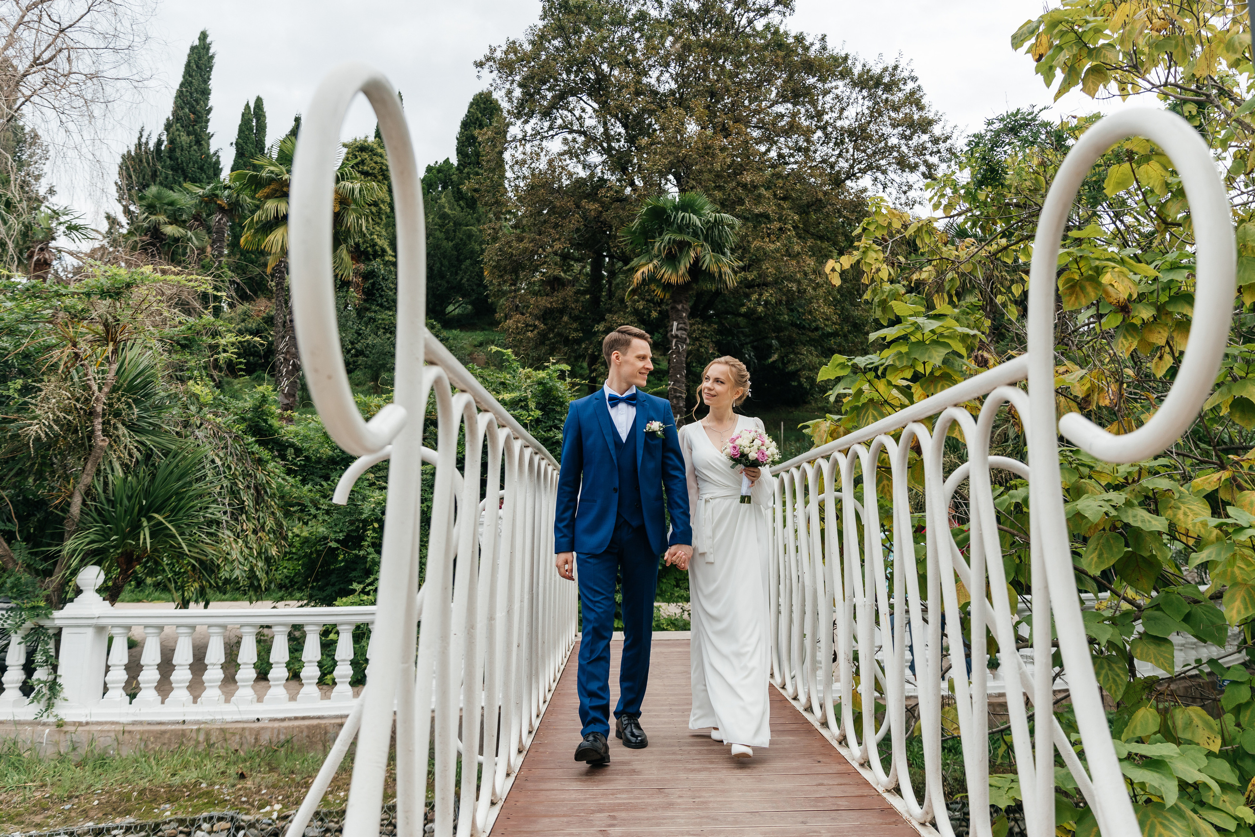 Супруги гуляют по мосту в парке в Адлере