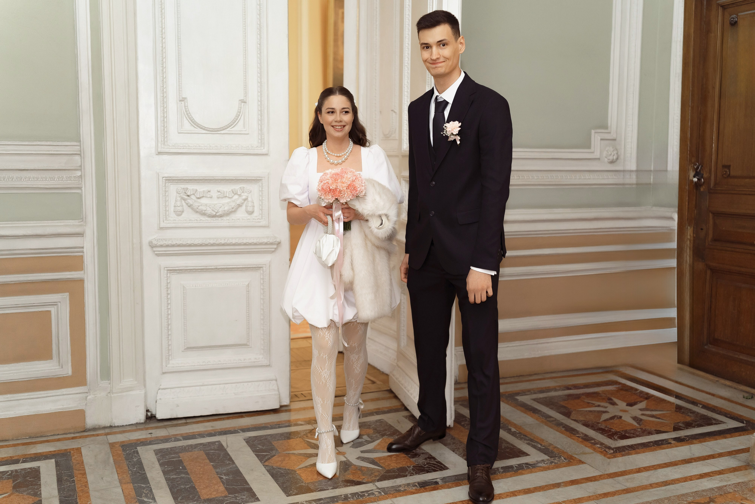 Молодожёны идут по дворцовому залу перед регистрацией брака в Санкт-Петербурге.