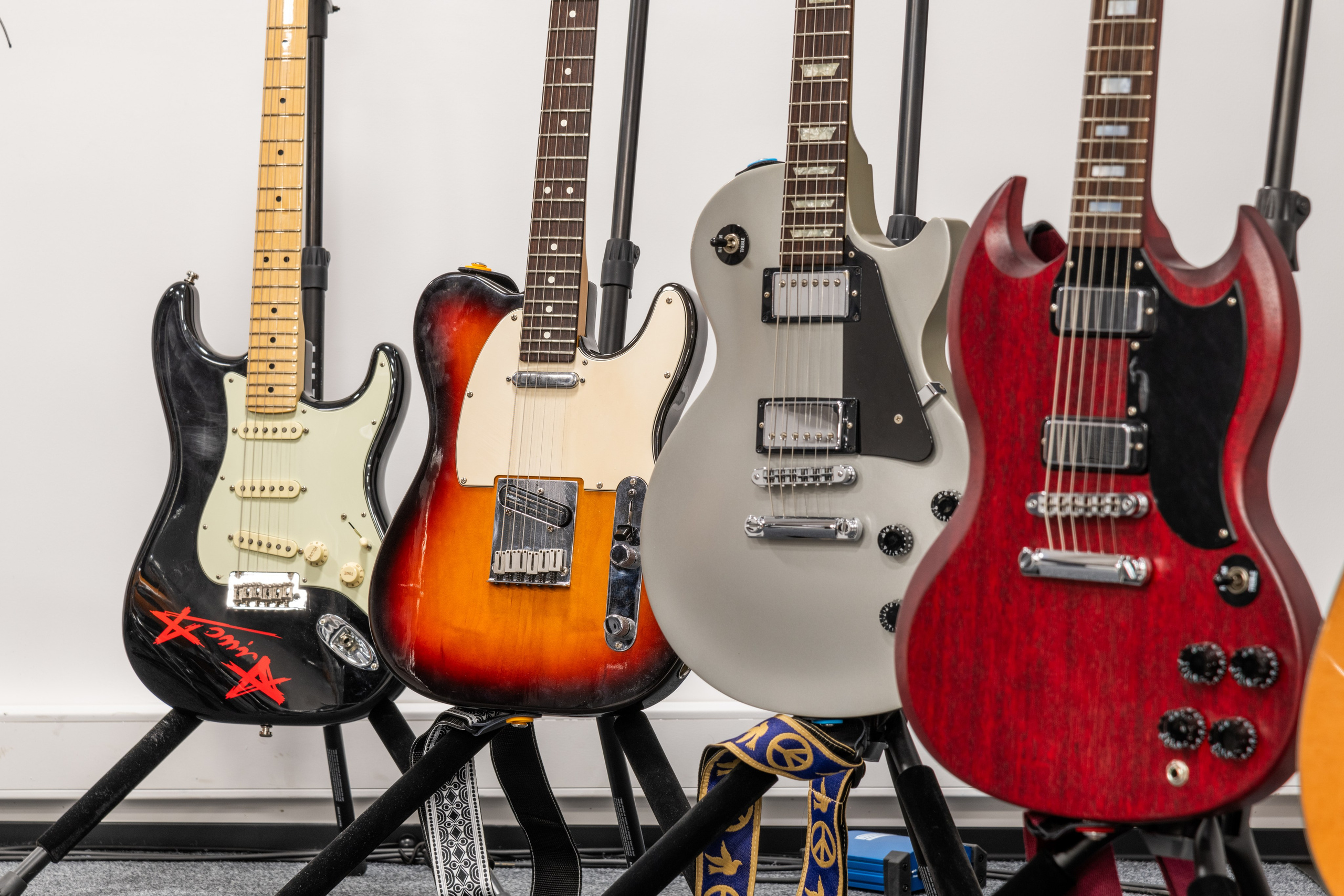 Детализированный вид электрических и акустических гитар на подставках различных цветов и дизайнов.