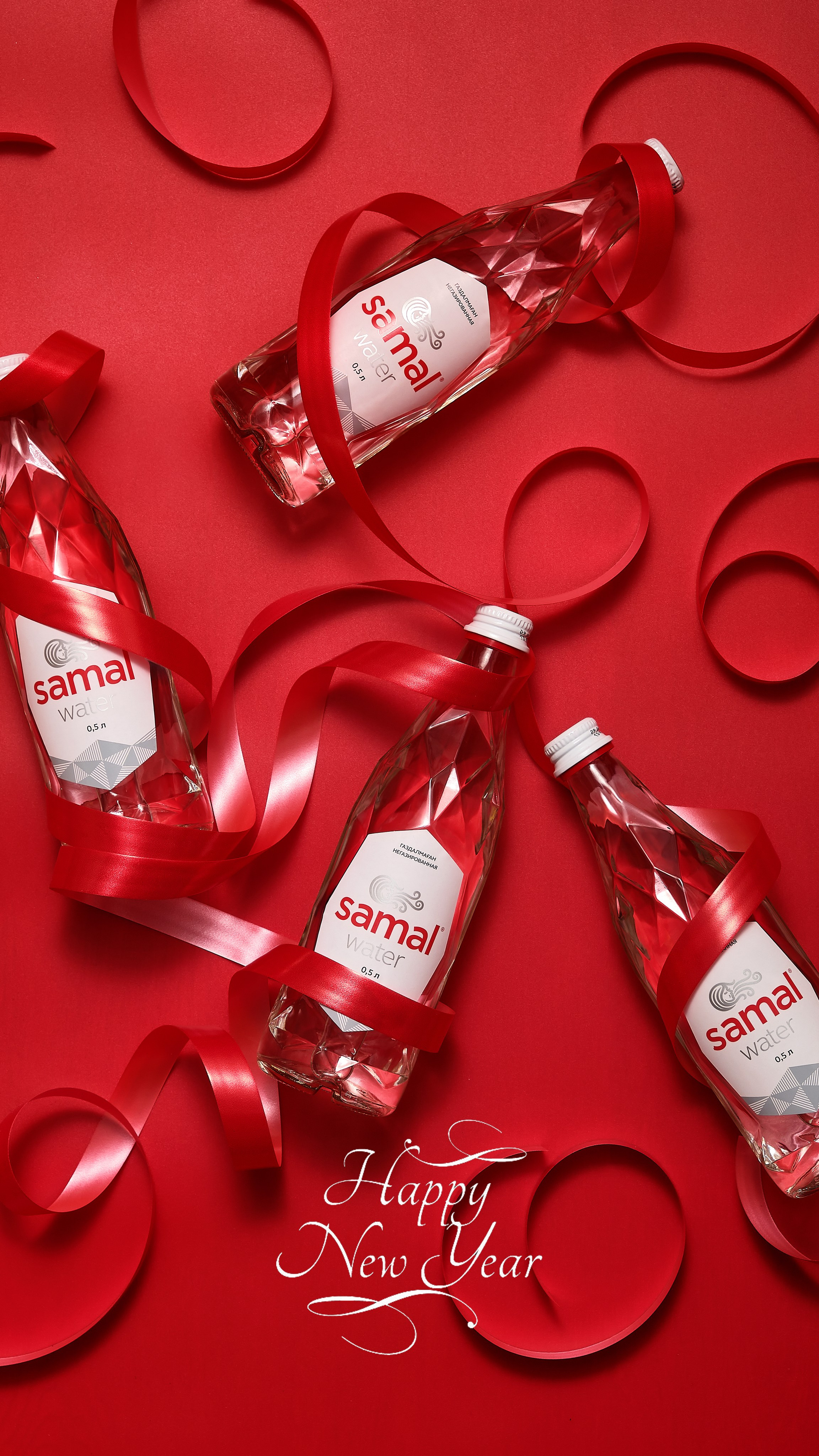 Предметная фотосъёмка минеральной воды в Алматы — несколько бутылок Samal с декоративными лентами на ярком фоне, студийная съёмка.