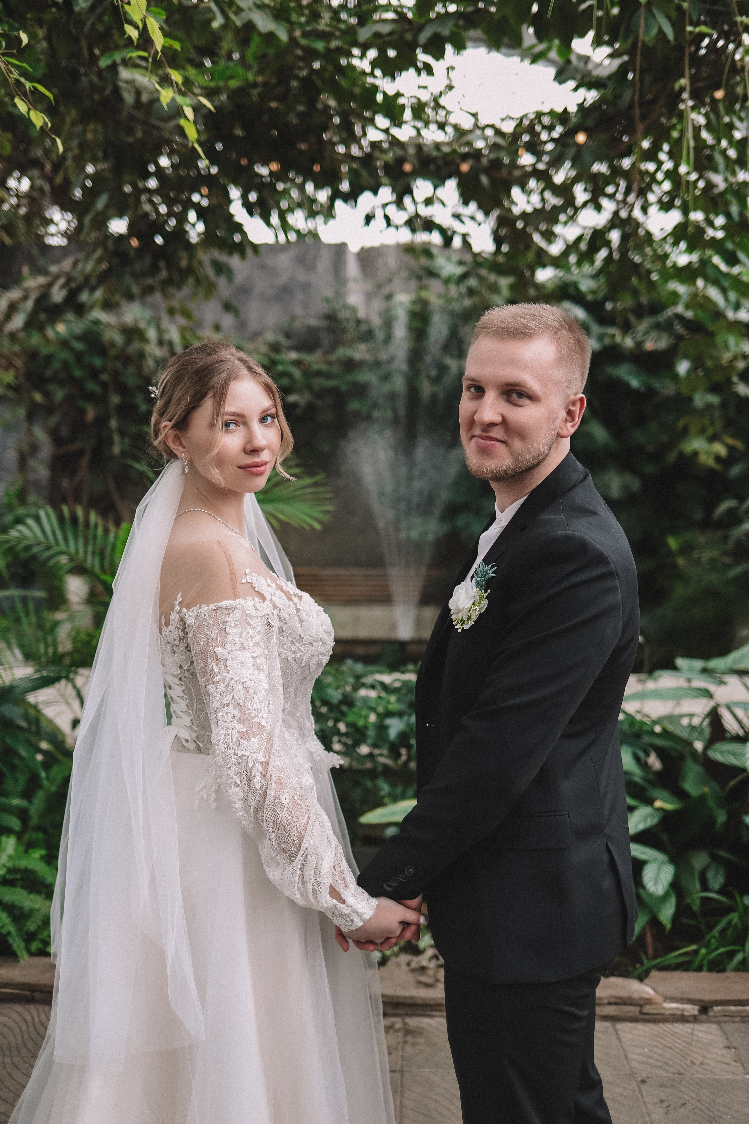 Молодожены держатся за руки, прогулка у воды