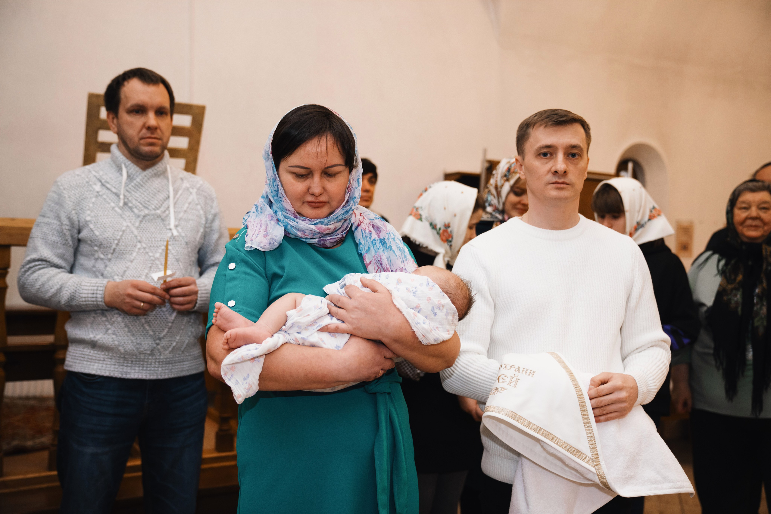 крестная держит на руках ребенка в церкви