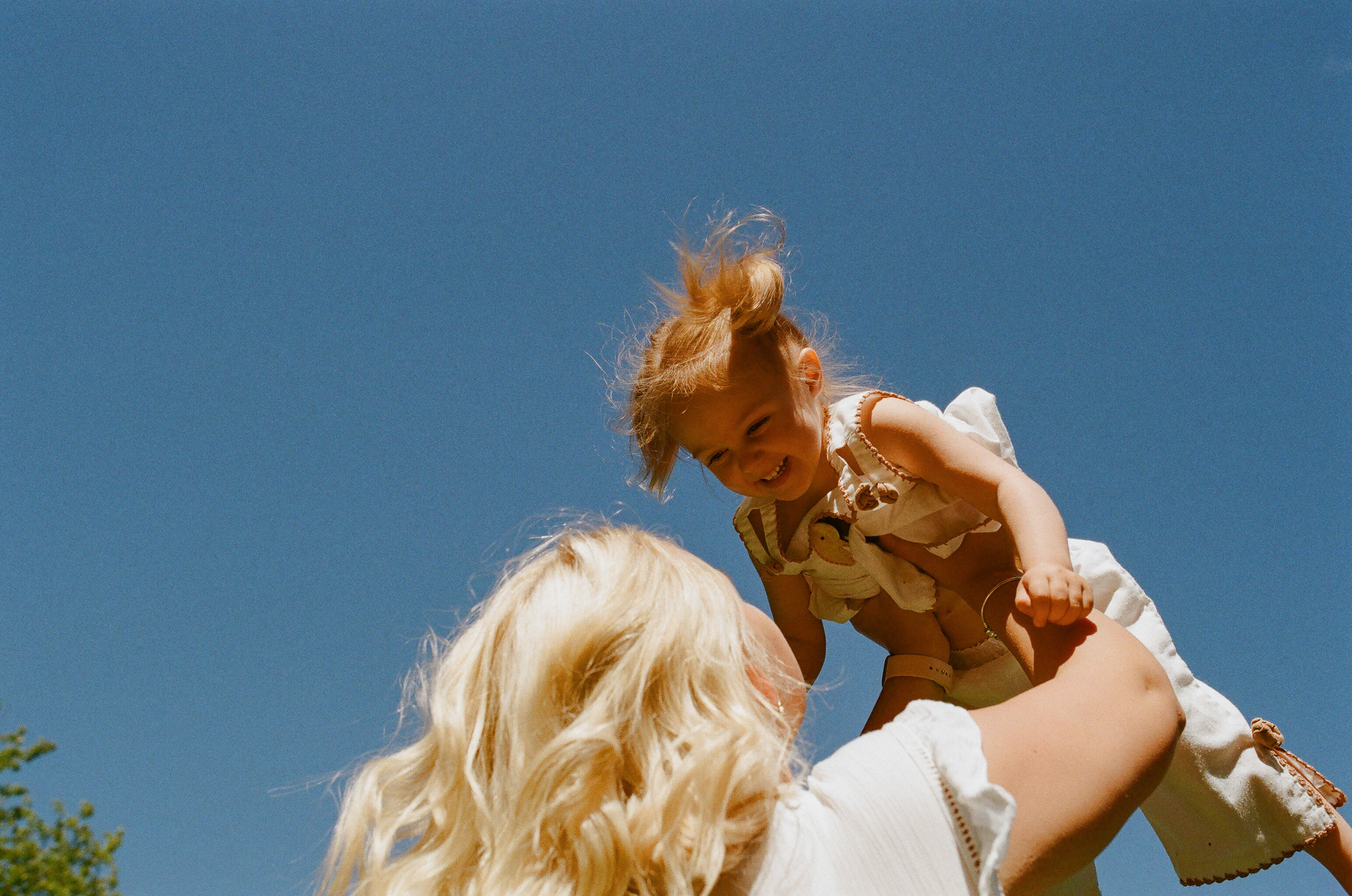a mother lifting her small daughter in the air, the daughter is laughing