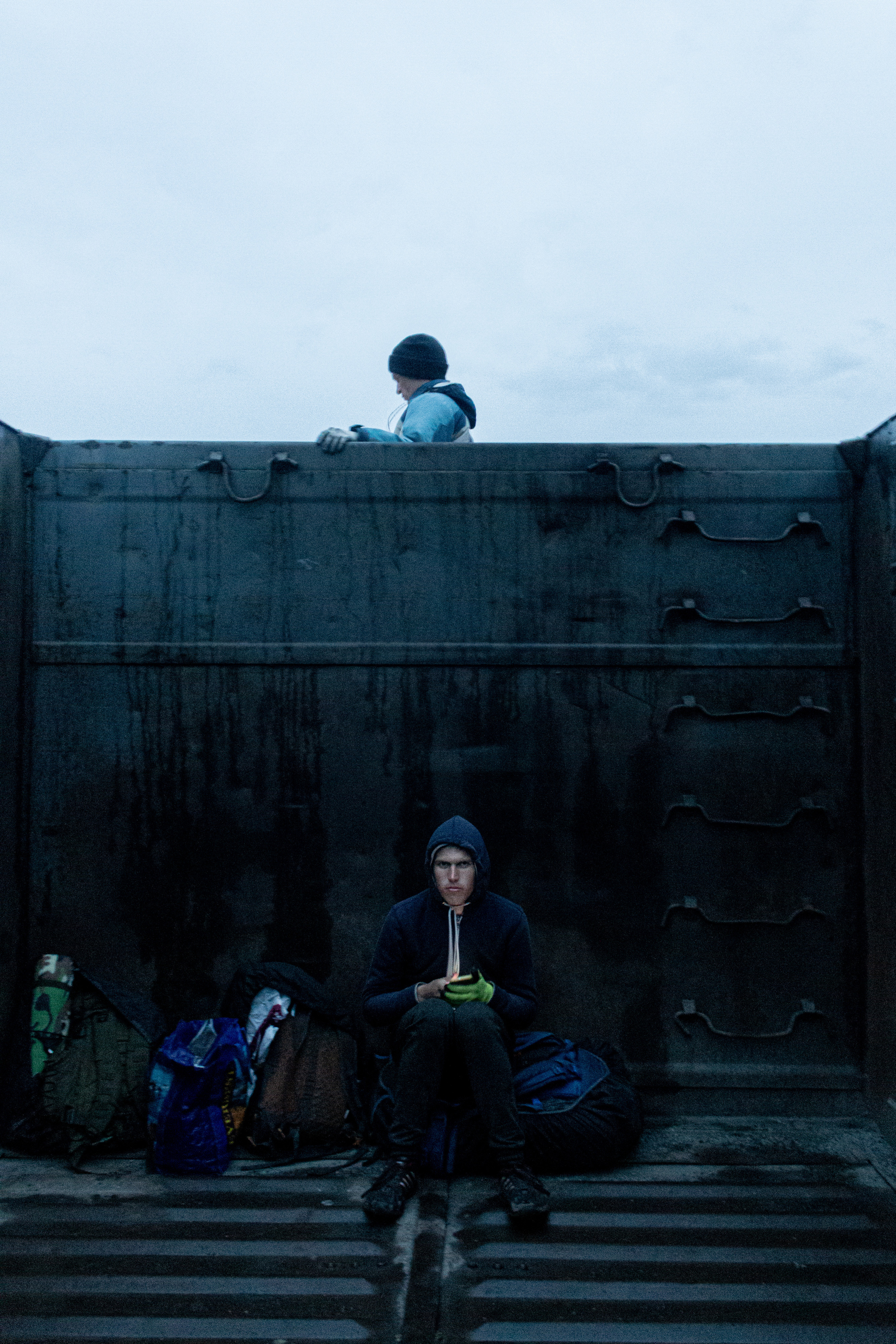 Vlad is busy with his phone while Vanya is admiring the vicinity from inbetween the wagons.