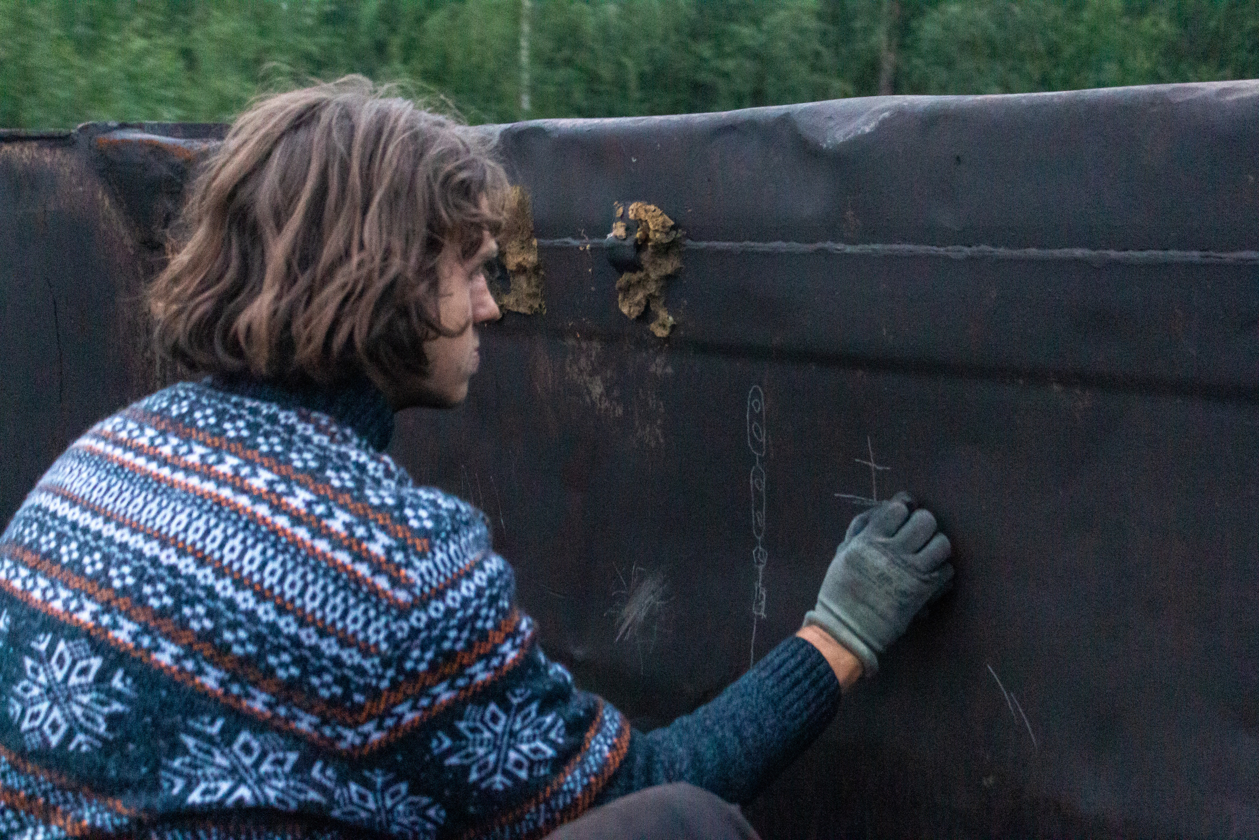 Edik drawing with a stone on the dirty open wagon wall.