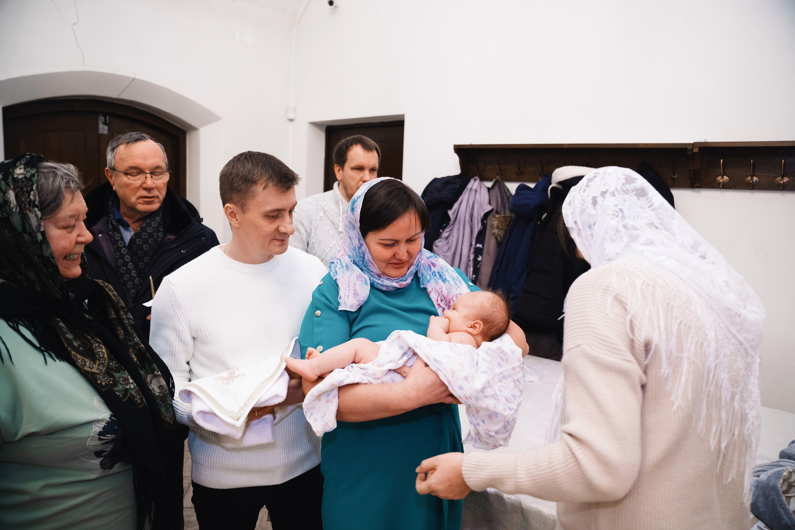 ребёнок на руках родственников во время крещения
