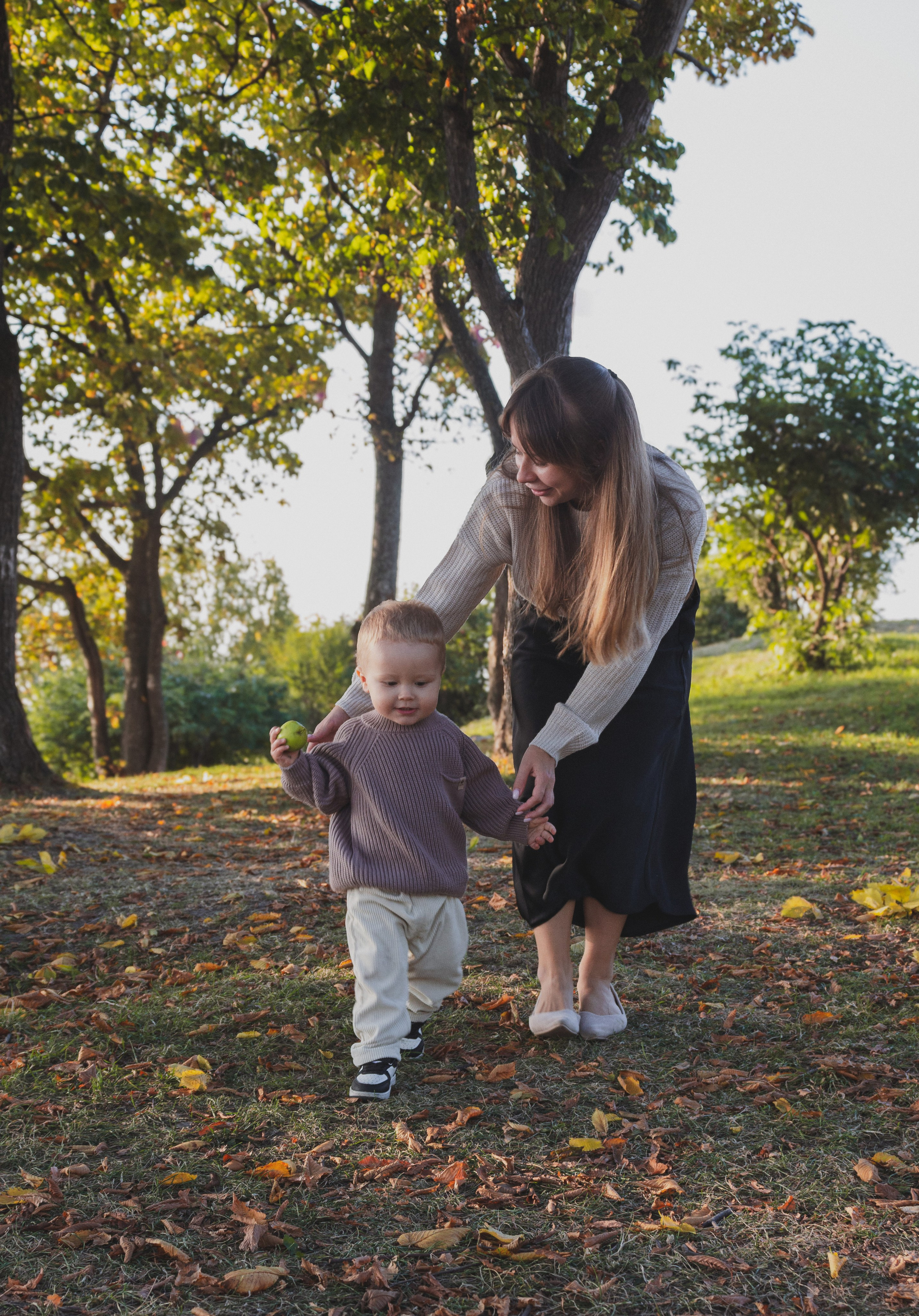 Мама гуляет с маленьким ребёнком в осеннем парке
