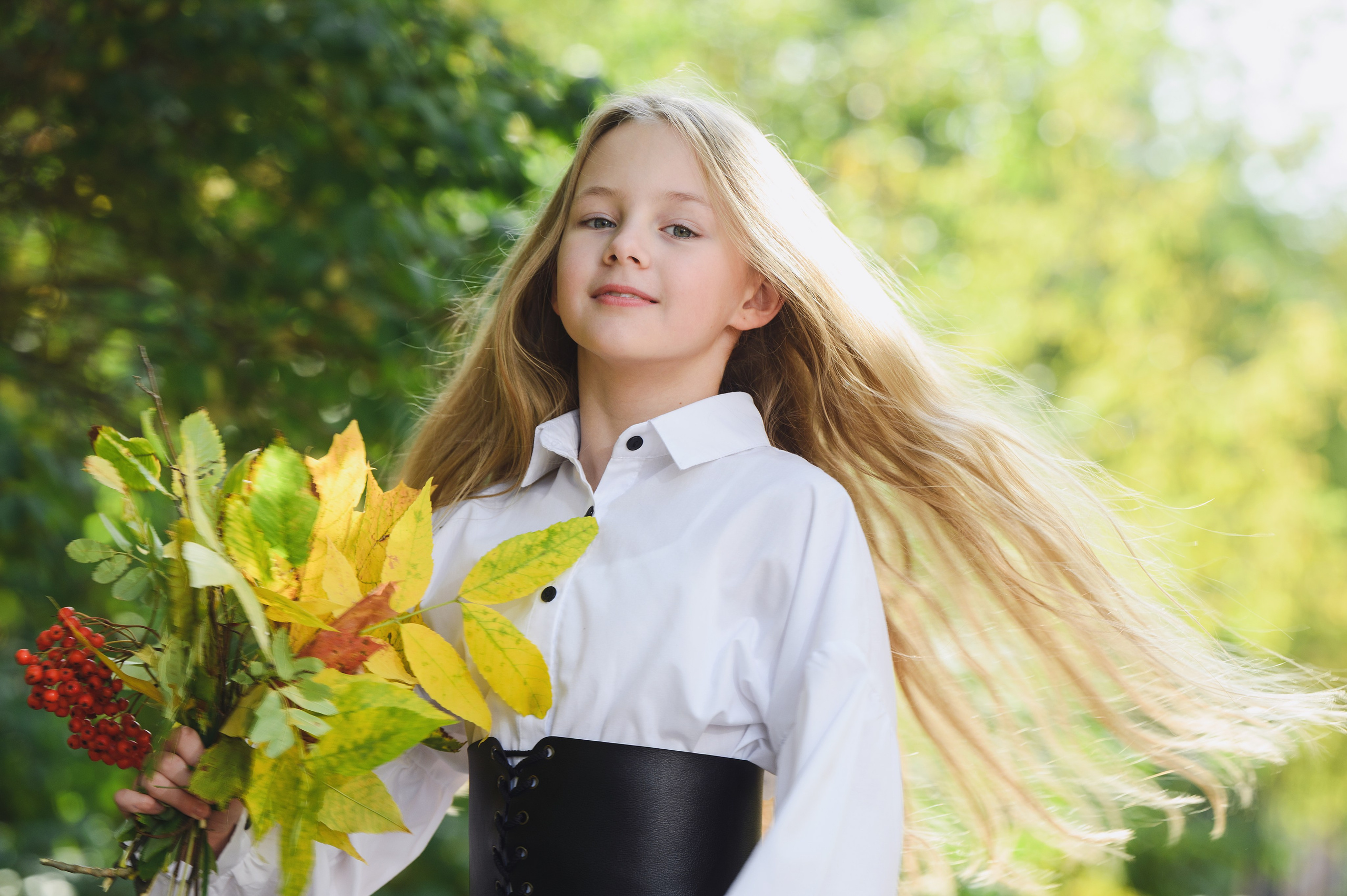 Школьница с букетом жёлтых цветов в солнечном саду