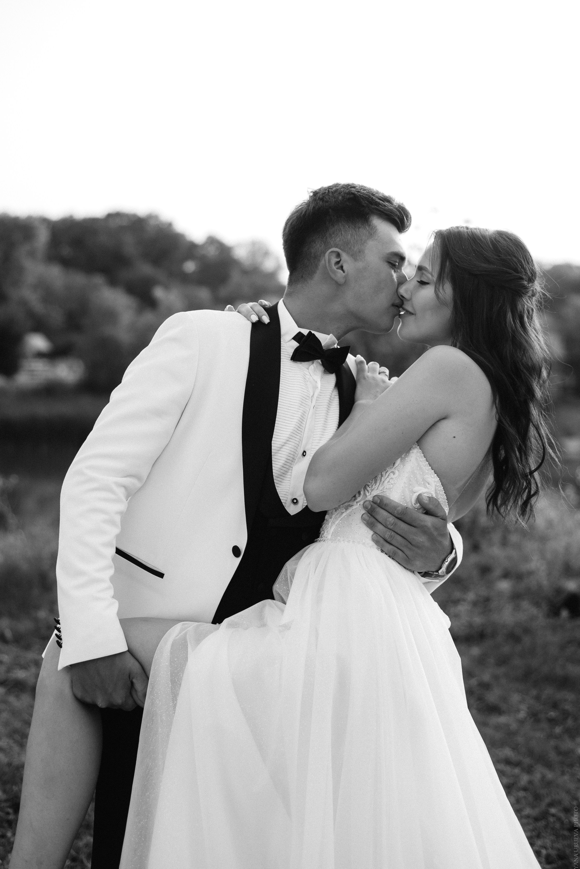 Жених в белом смокинге целует невесту