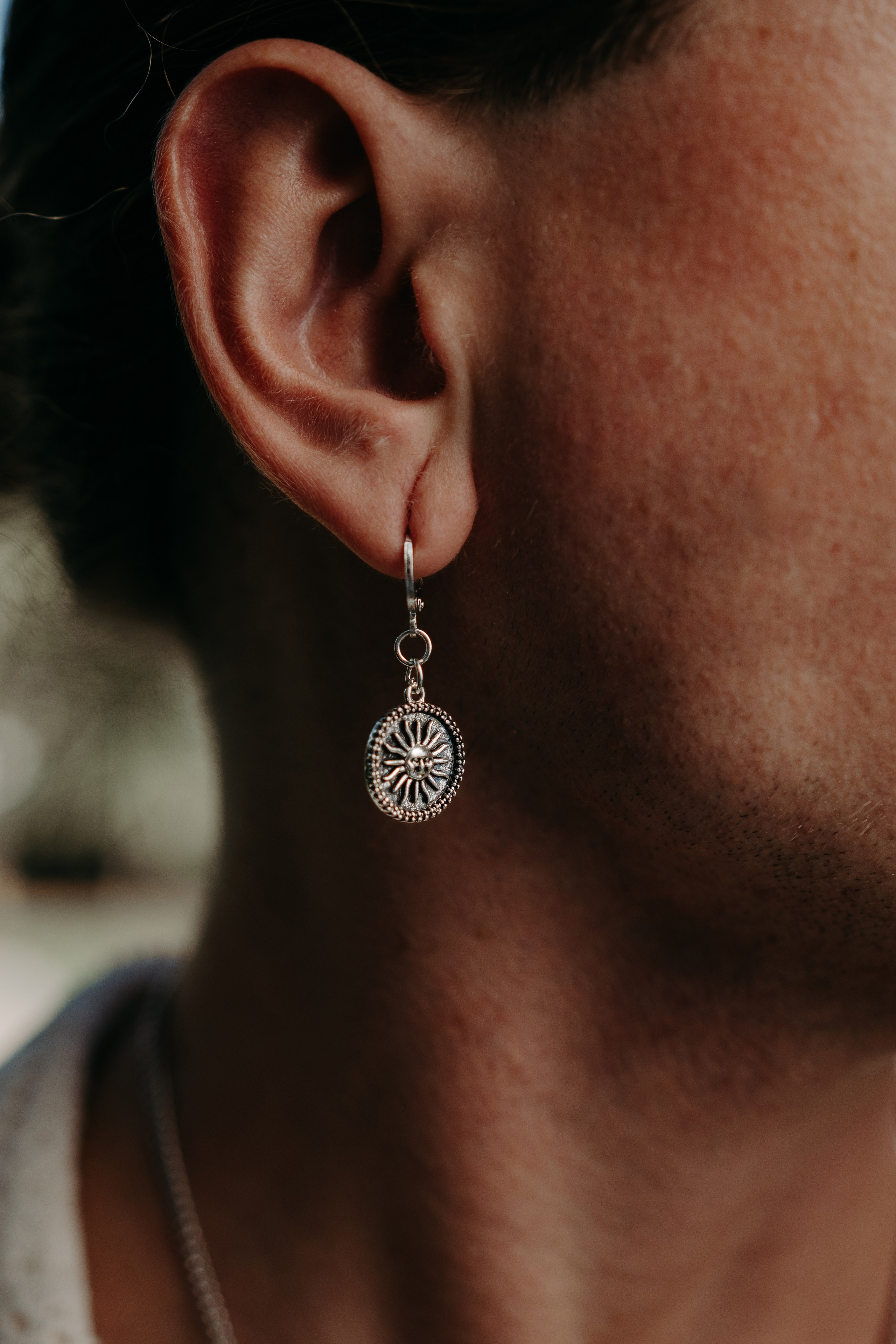 Close-up of dangling silver earrings styled with a white blouse, representing sophistication.