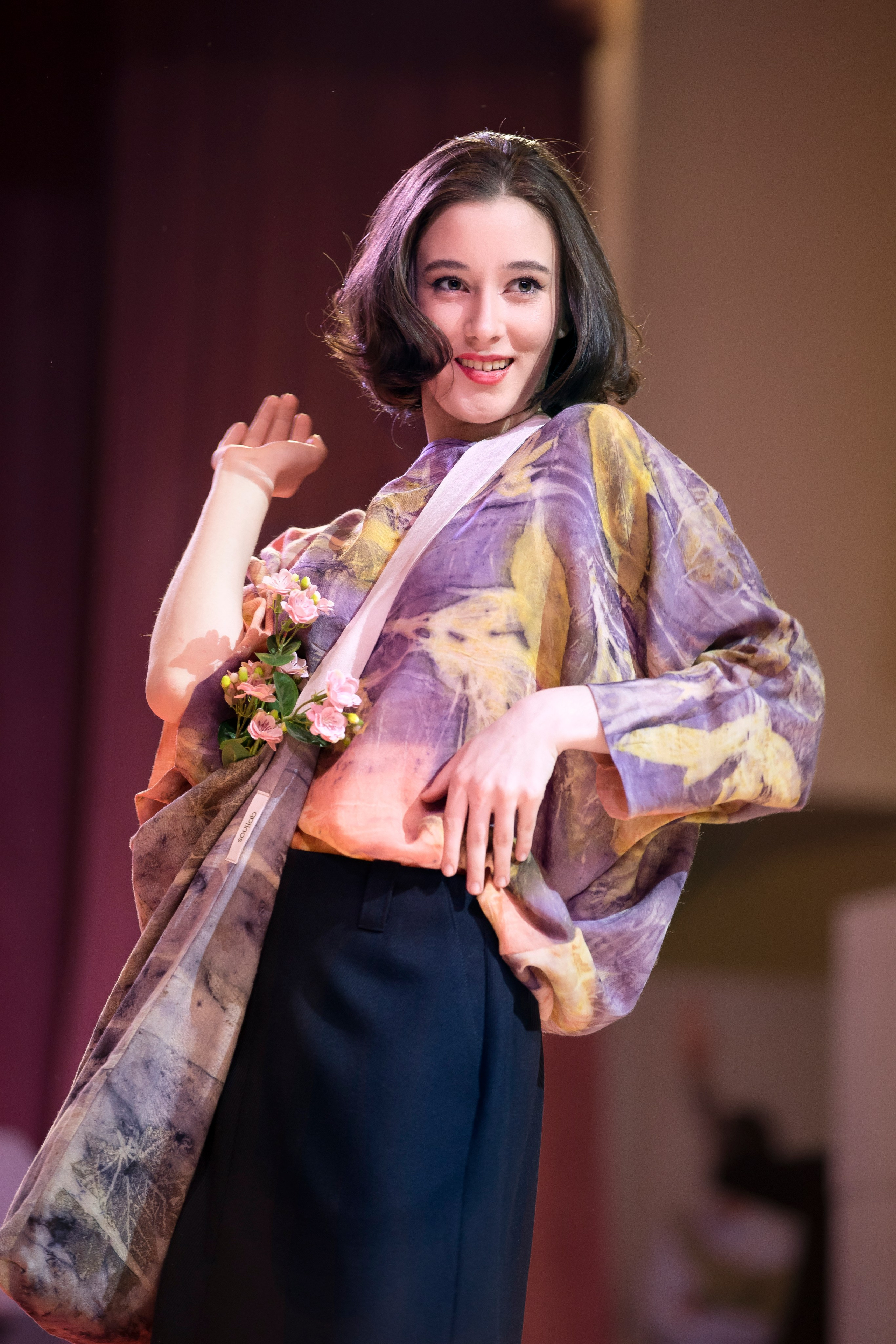 Модель с цветным каре, сумкой через плечо, разворот, улыбается и смотрит в камеру на ED Fashion Show New Names 2024.