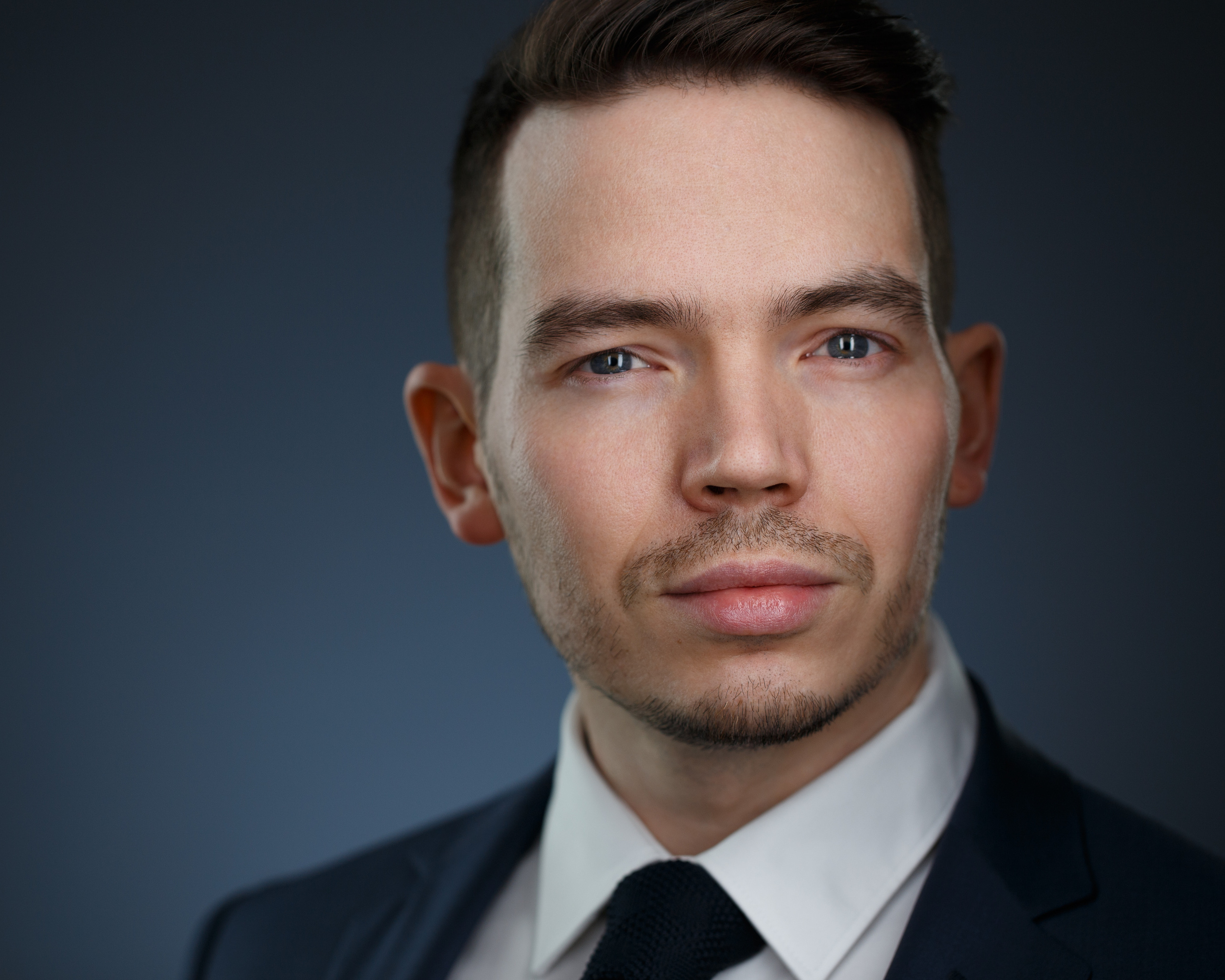 Бизнес-портрет молодого человека на тёмном фоне.