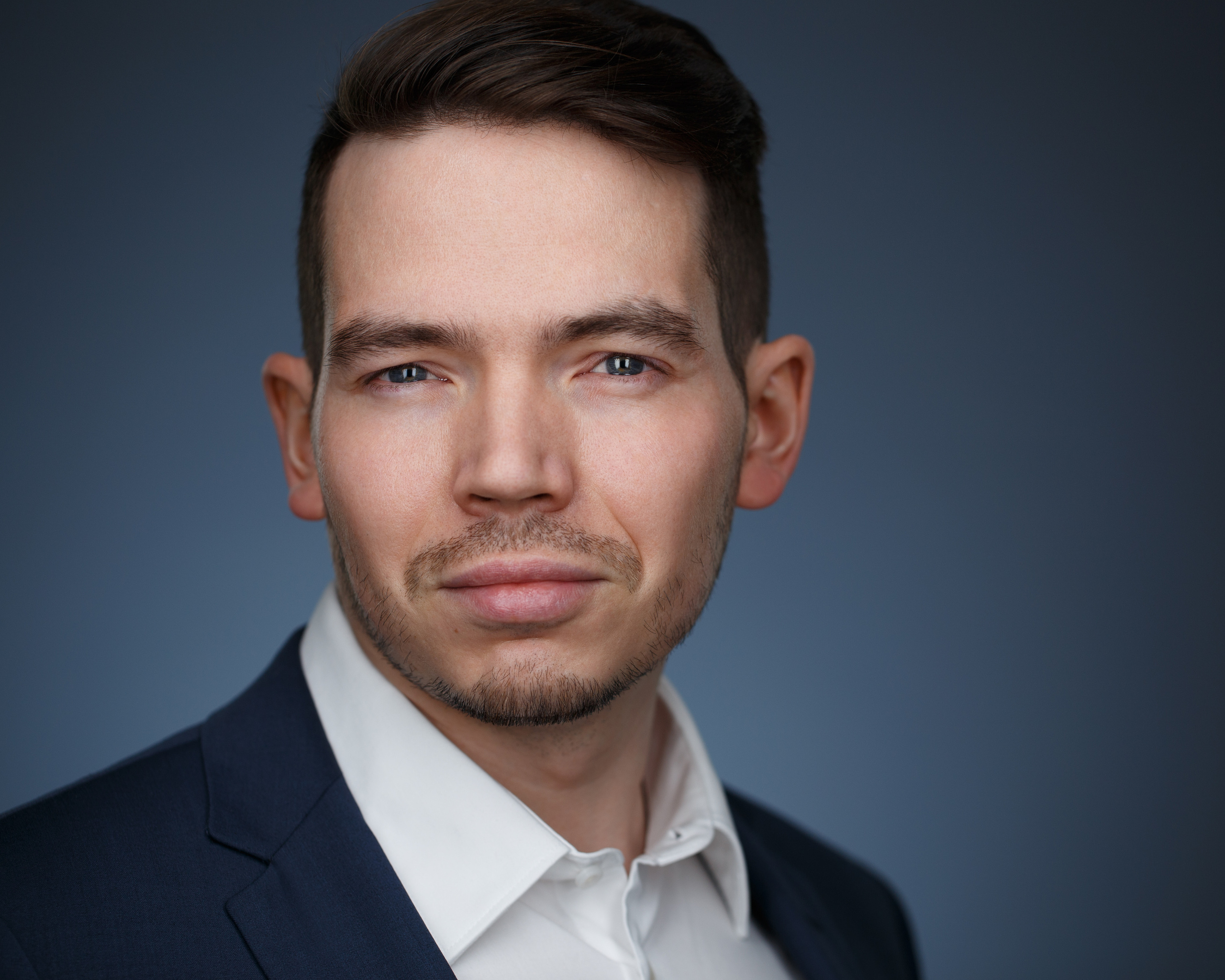 Деловой портрет молодого мужчины на тёмном фоне.