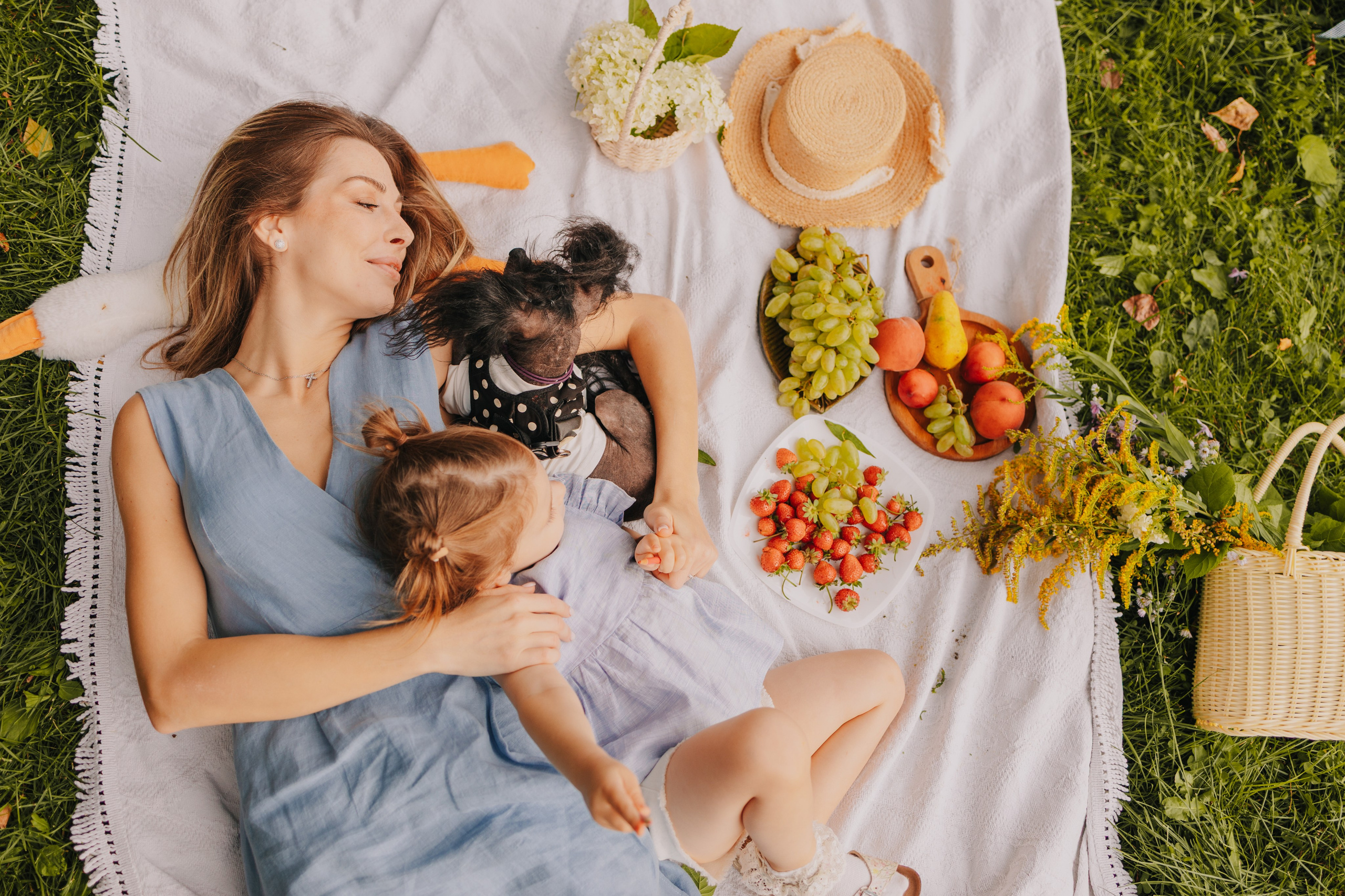 Мама с дочкой сидят на пледе в поле во время фотосессии