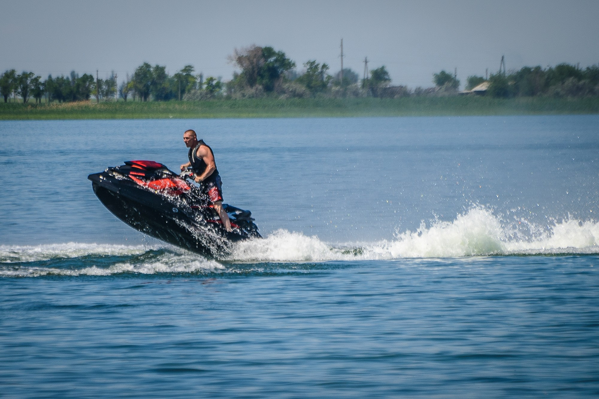 Мужчина на водном скутере мчится по воде, поднимая брызги