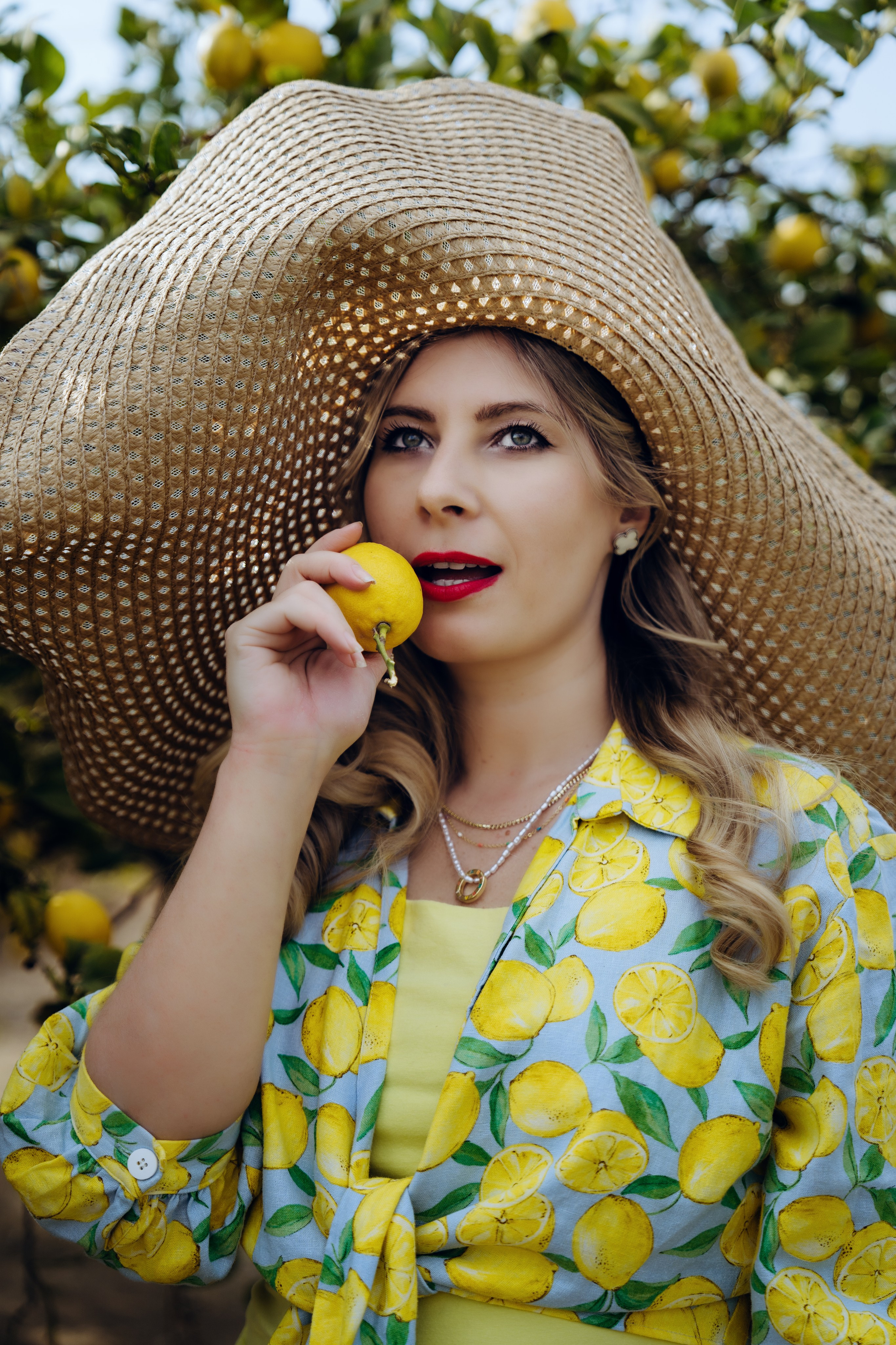 девушка пробует лимон в саду в шляпе