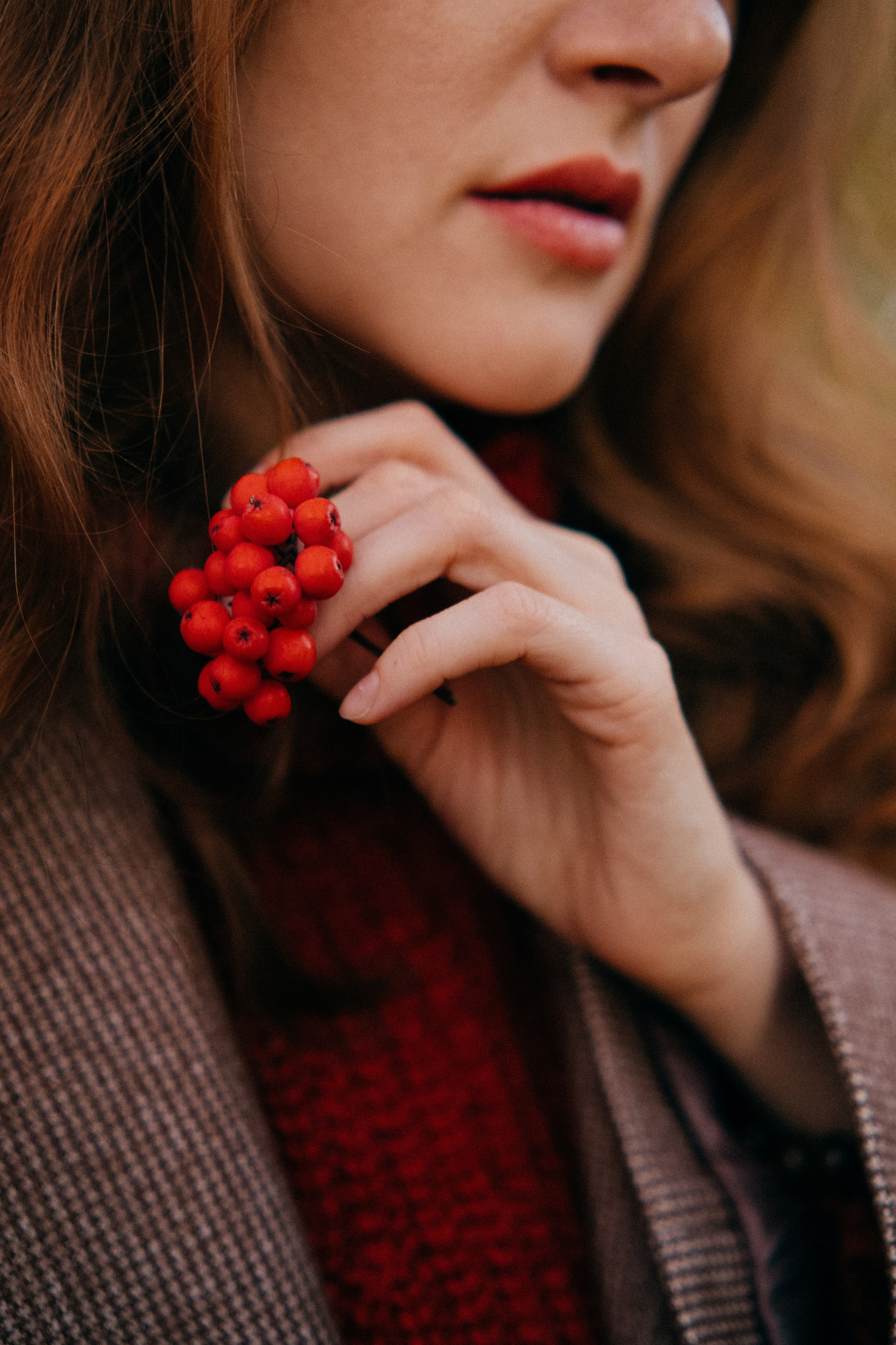 Крупное детальное фото гроздь рябины в руке рыжей девушки в пальто