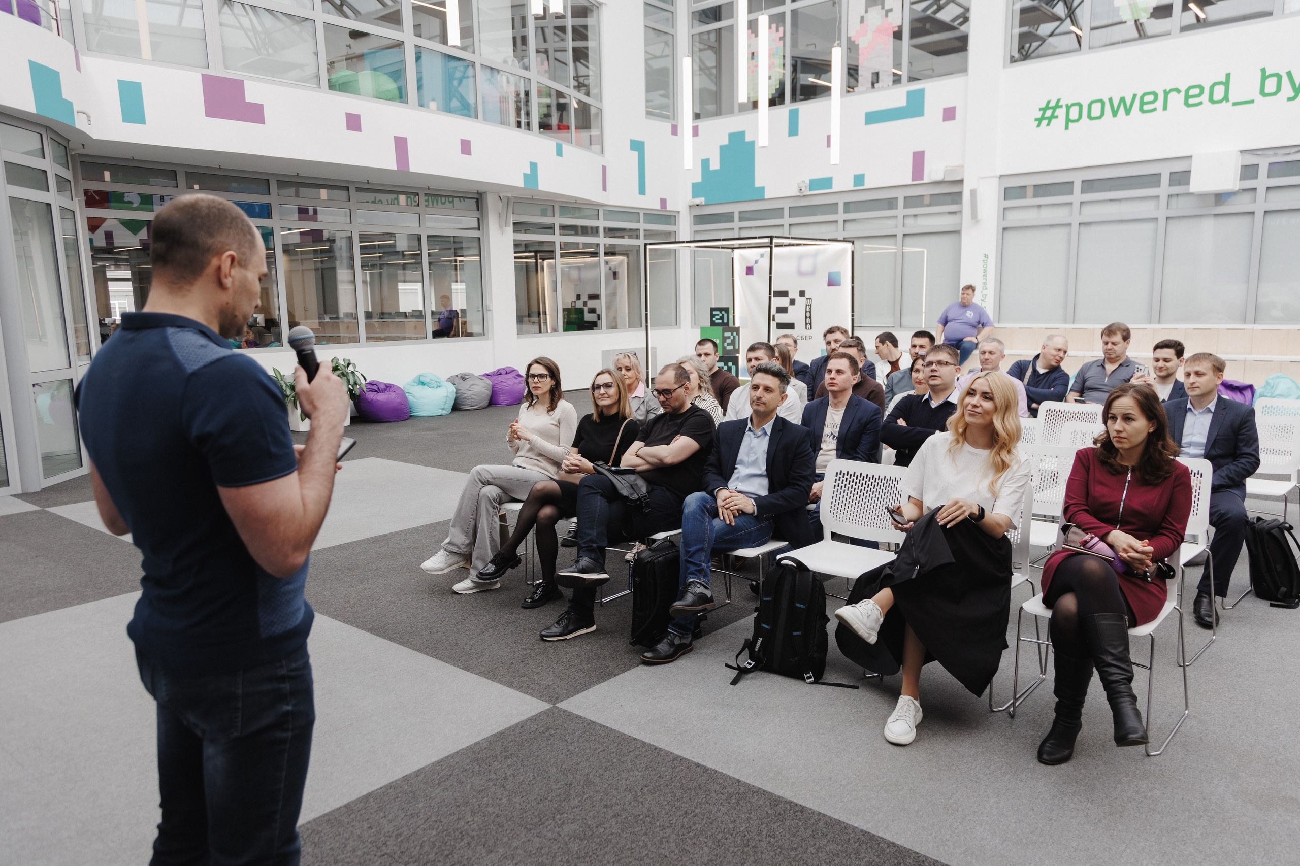 Общая картина: спикер на сцене и реакция большой аудитории в зале.