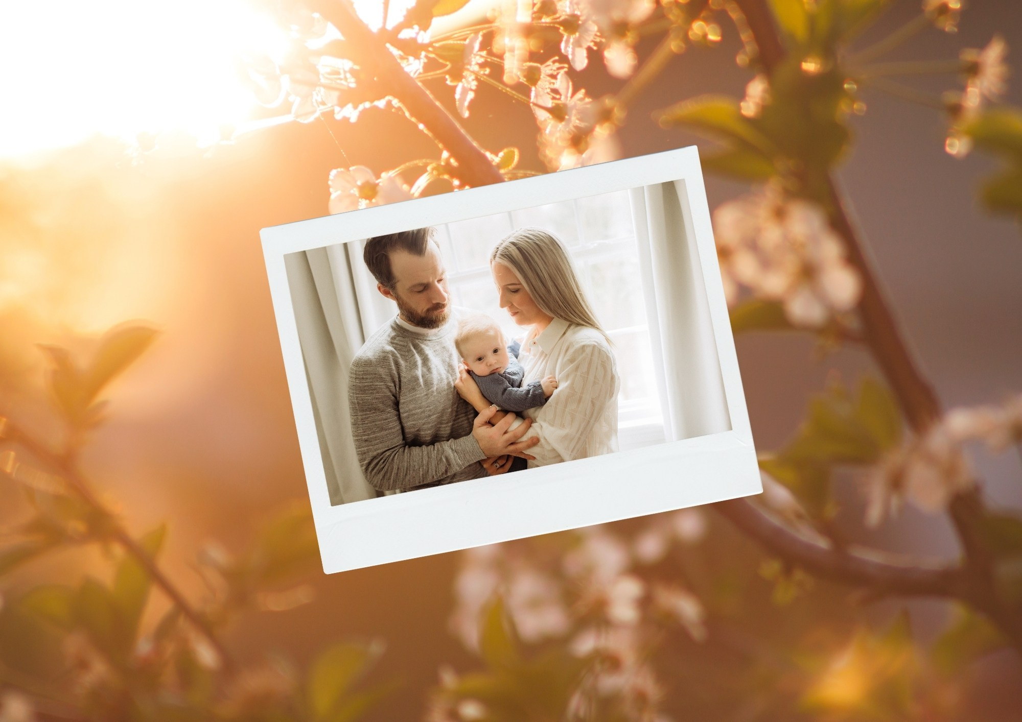 молодые родители с малышом на руках на фоне весеннего цветения