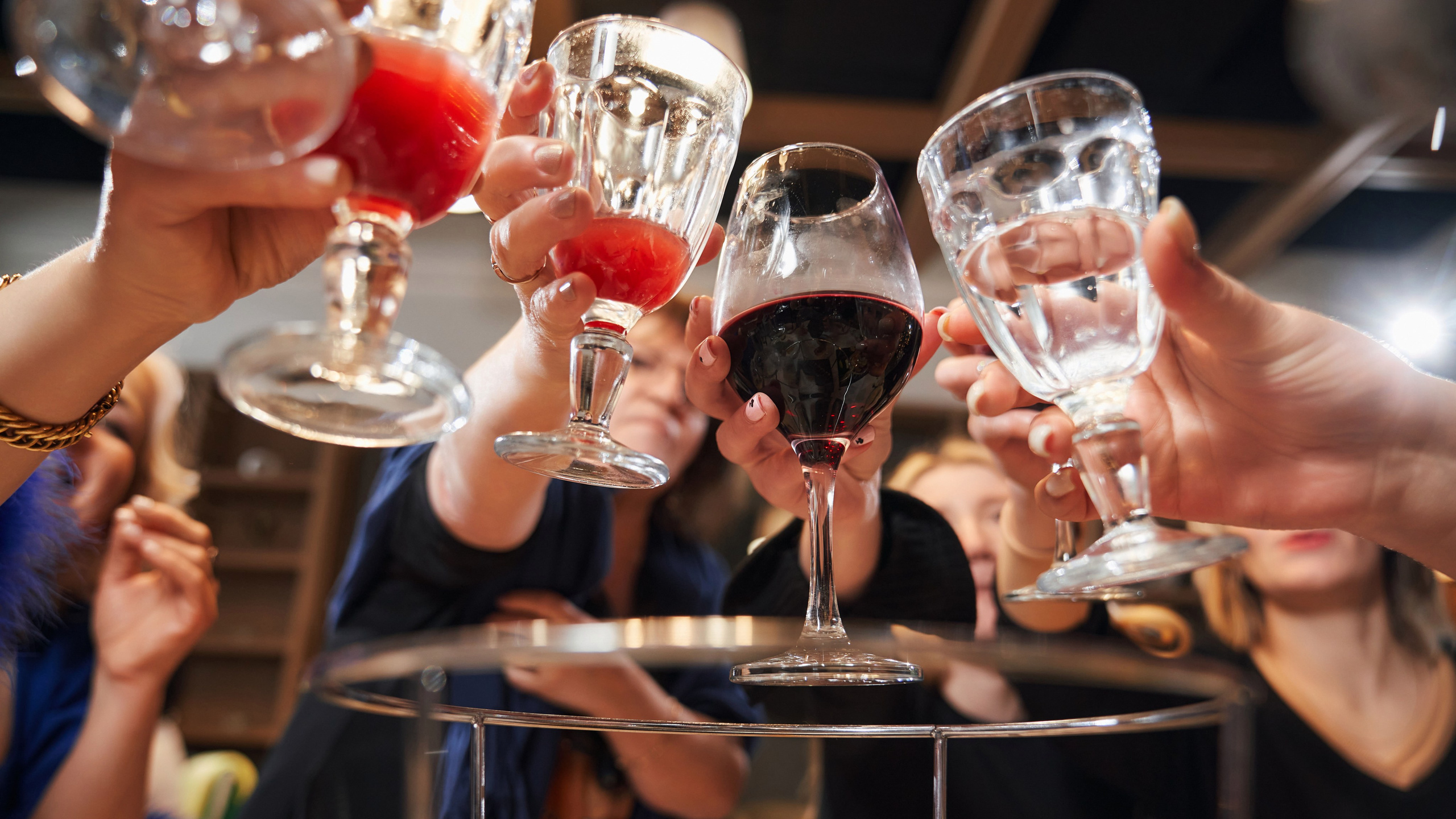 бокалы с напитками в руках на праздничном застолье