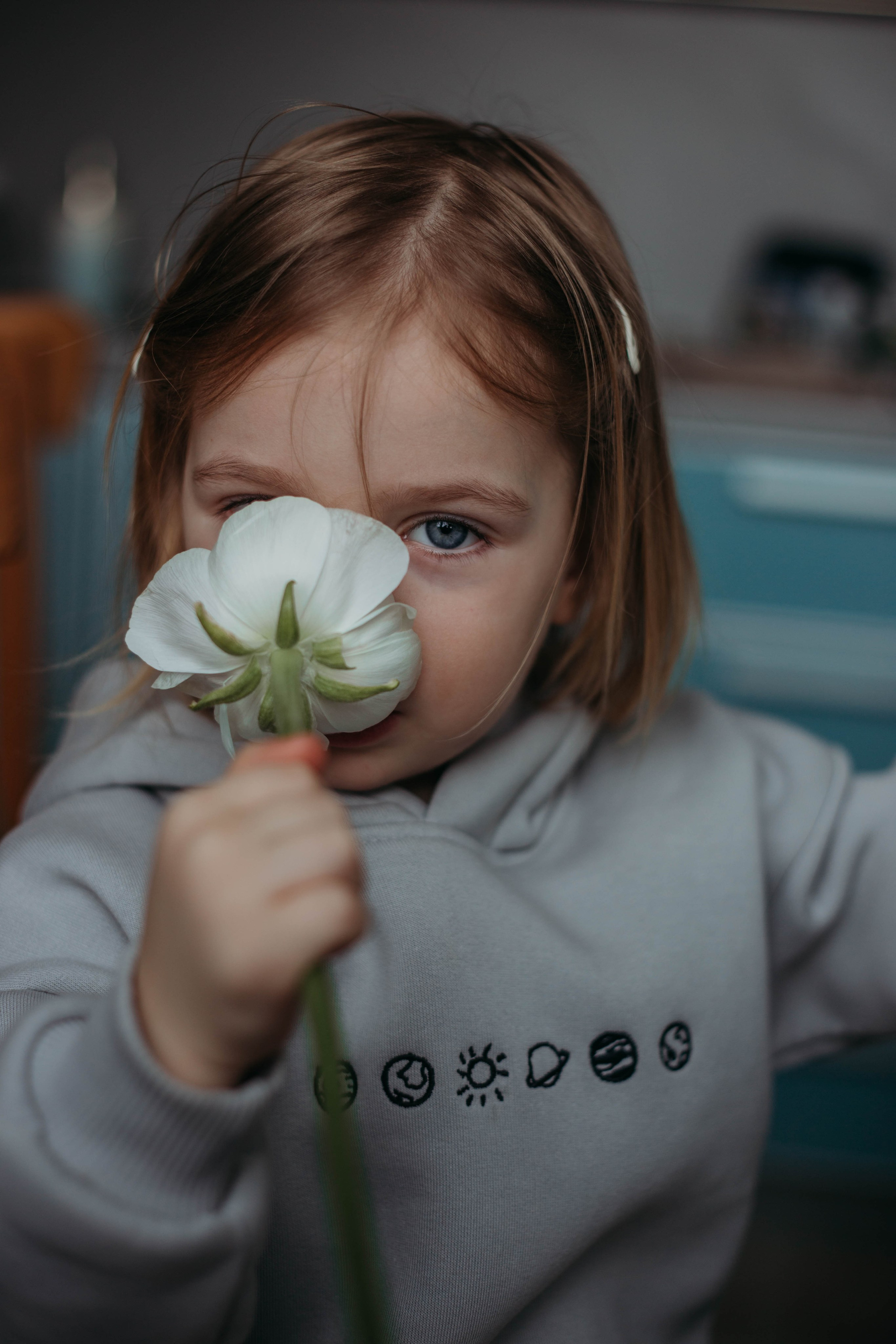 девочка нюхает цветок и смотрит тебе прямо в камеру