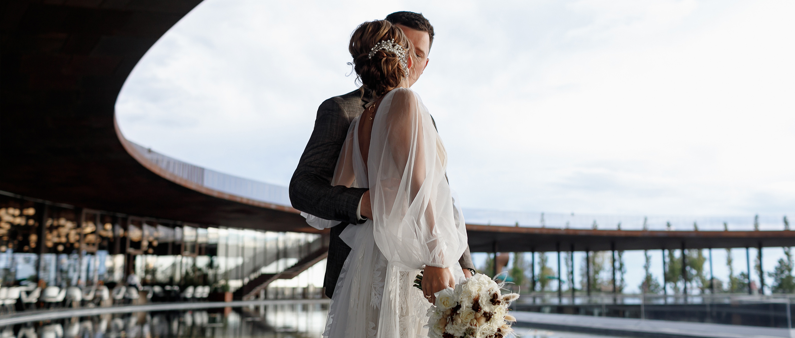 Жених и Невест целуются, нежно обнимая друг друга.