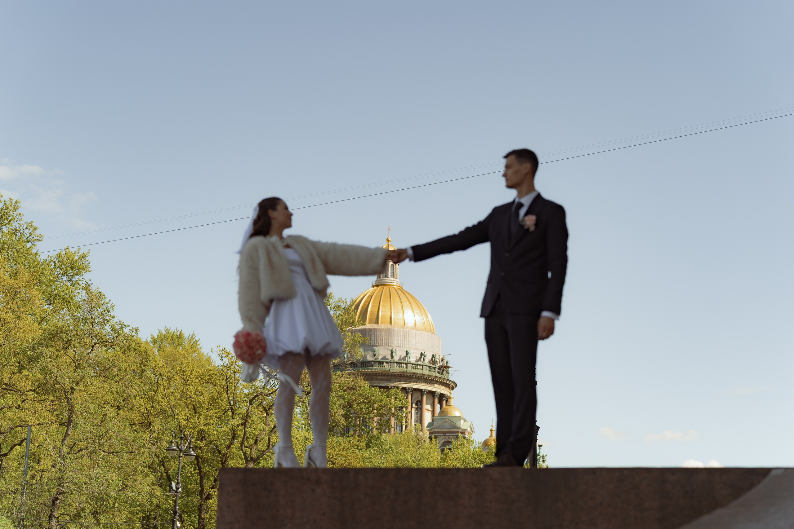 Жених и невеста держатся за руки на фоне купола Исаакия, романтичная прогулка после ЗАГСа