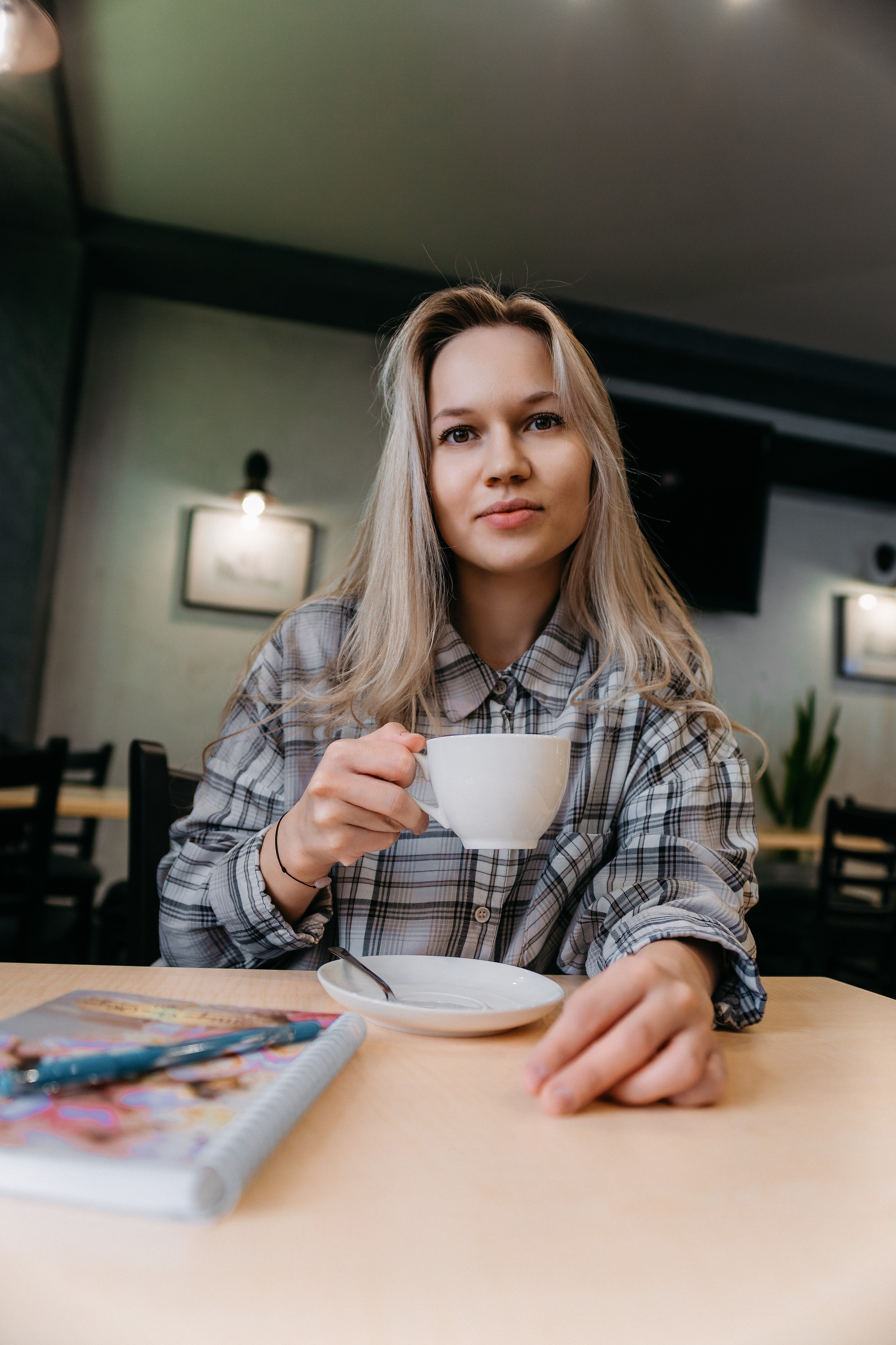 Девушка со светлыми волосами в кафе за столом