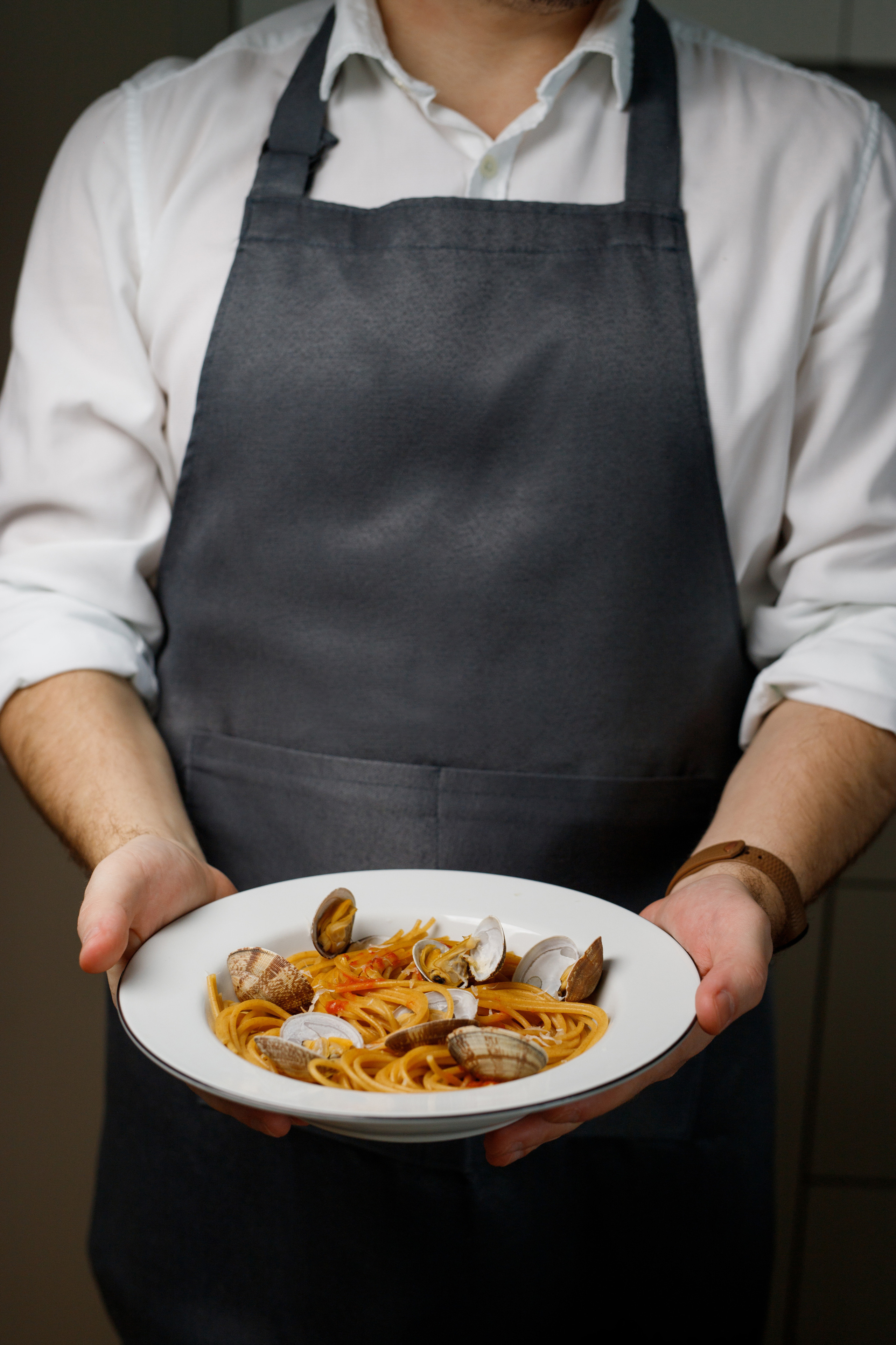 Фотосъемка еды в Астрахани, съемка еды в Астрахани, Спагетти с ракушками, мужчина в фартуке держит блюдо.
