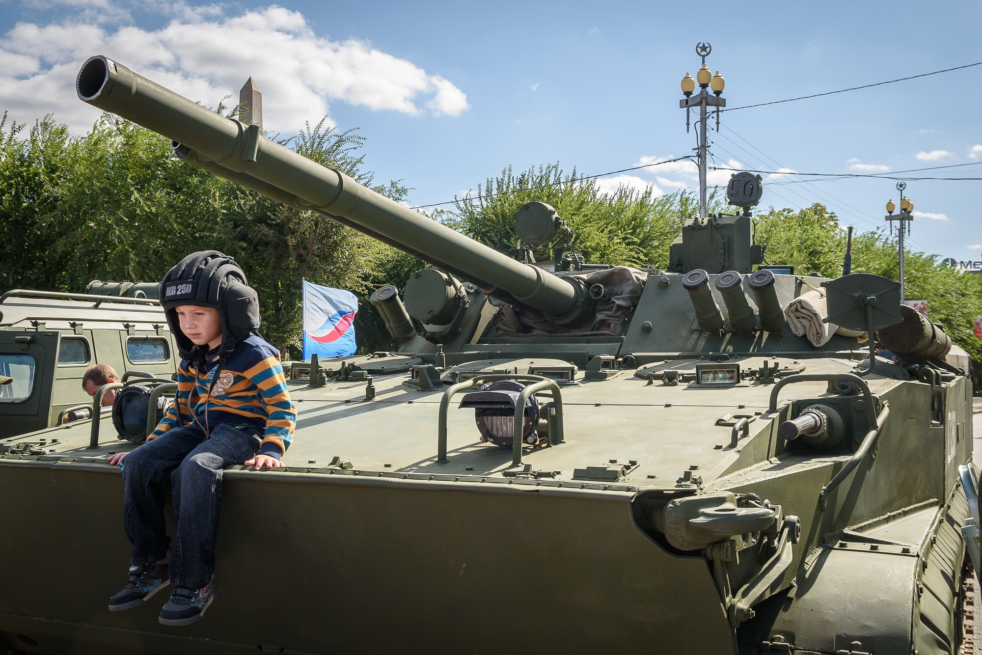 Ребенок в шлеме танкиста сидит на броне танка