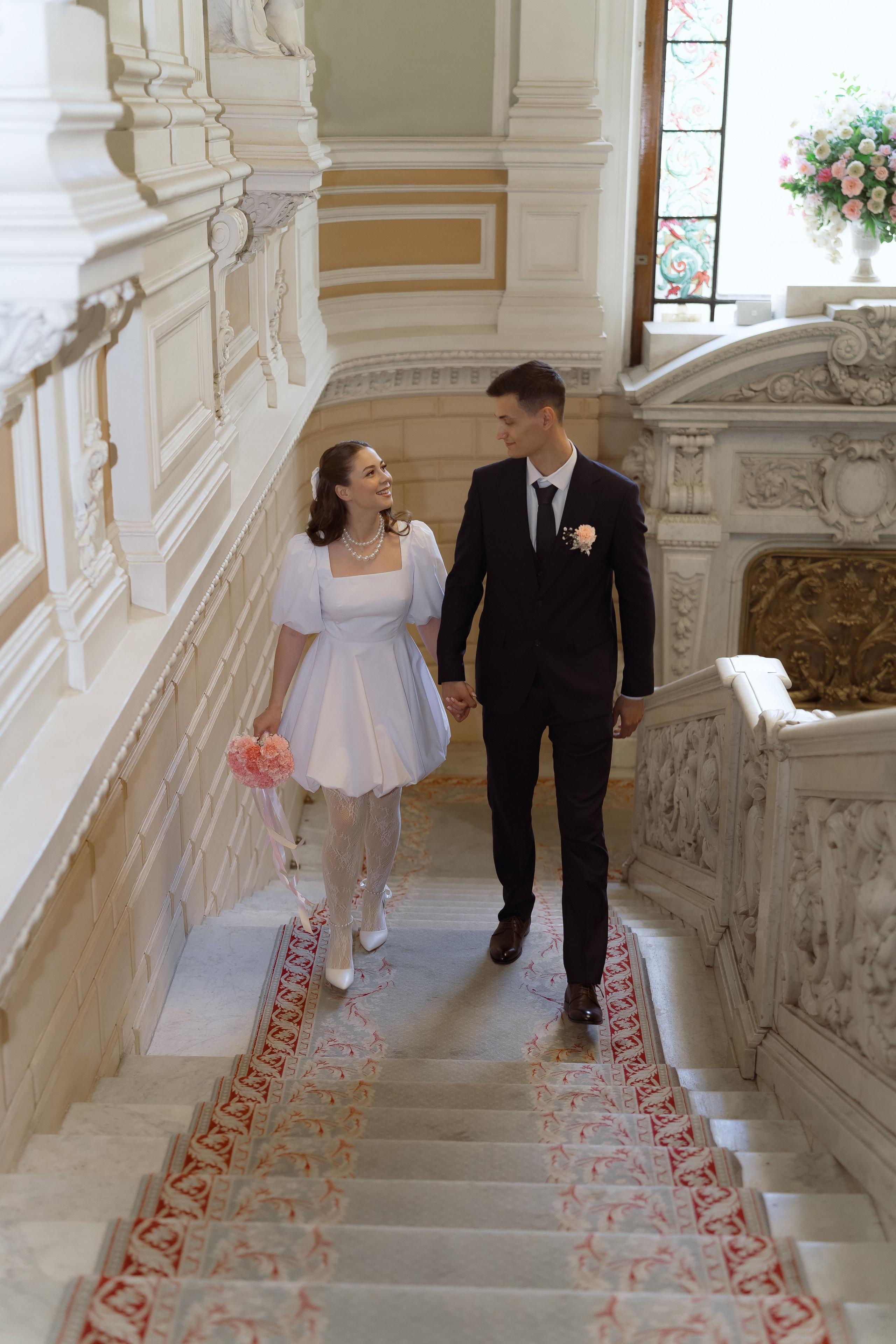 Молодожёны идут по лестнице дворца бракосочетания в Санкт-Петербурге