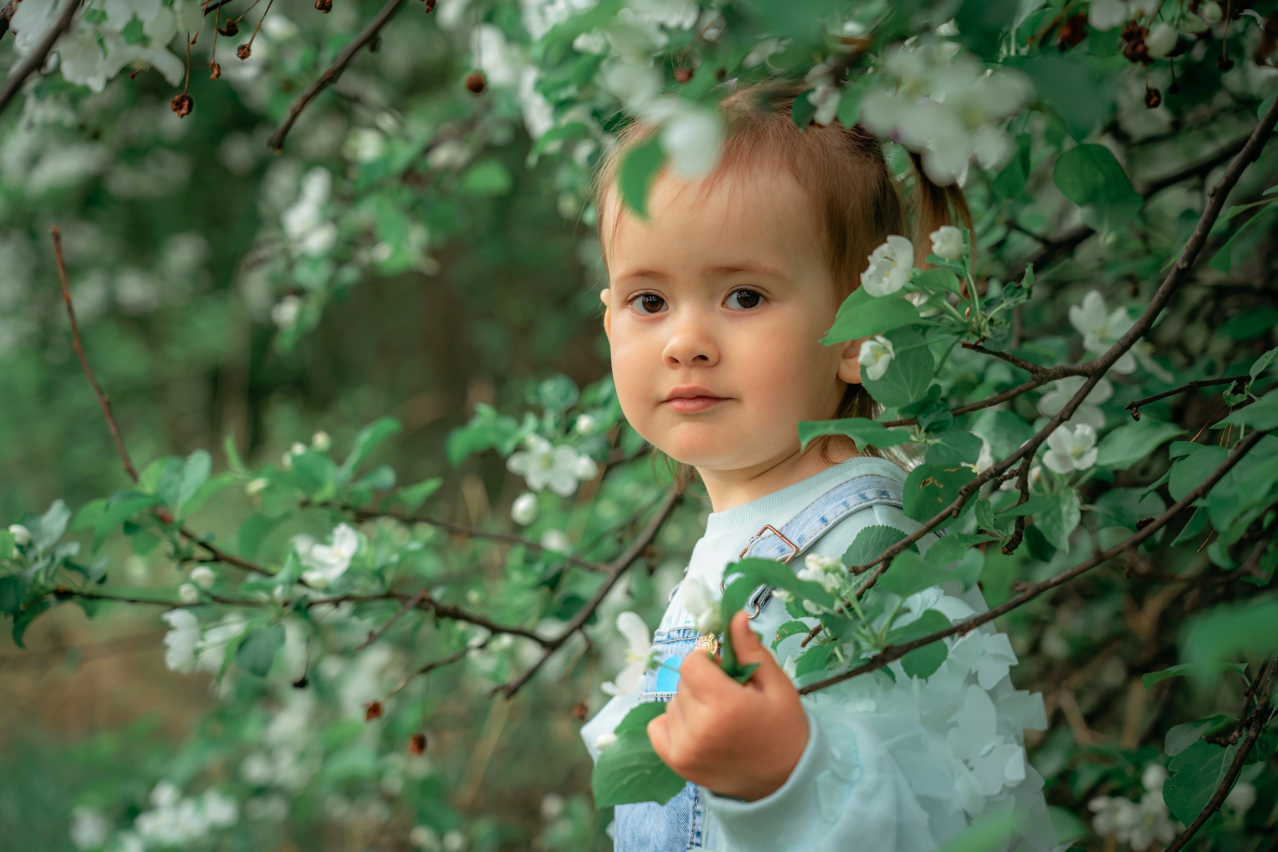 Маленькая девочка в цветущем яблоневом саду