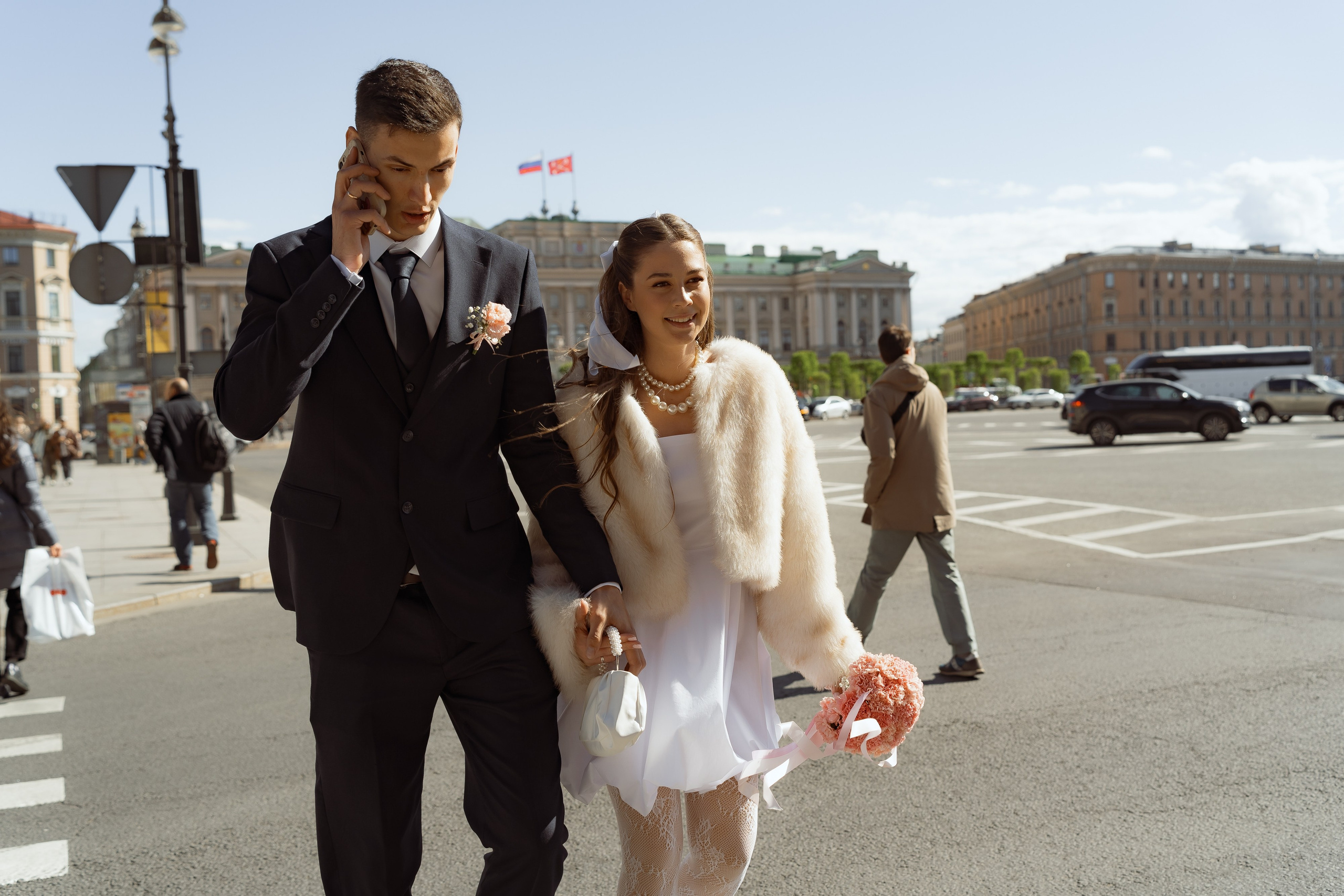 Жених и невеста смеются во время прогулки по центру Санкт-Петербурга