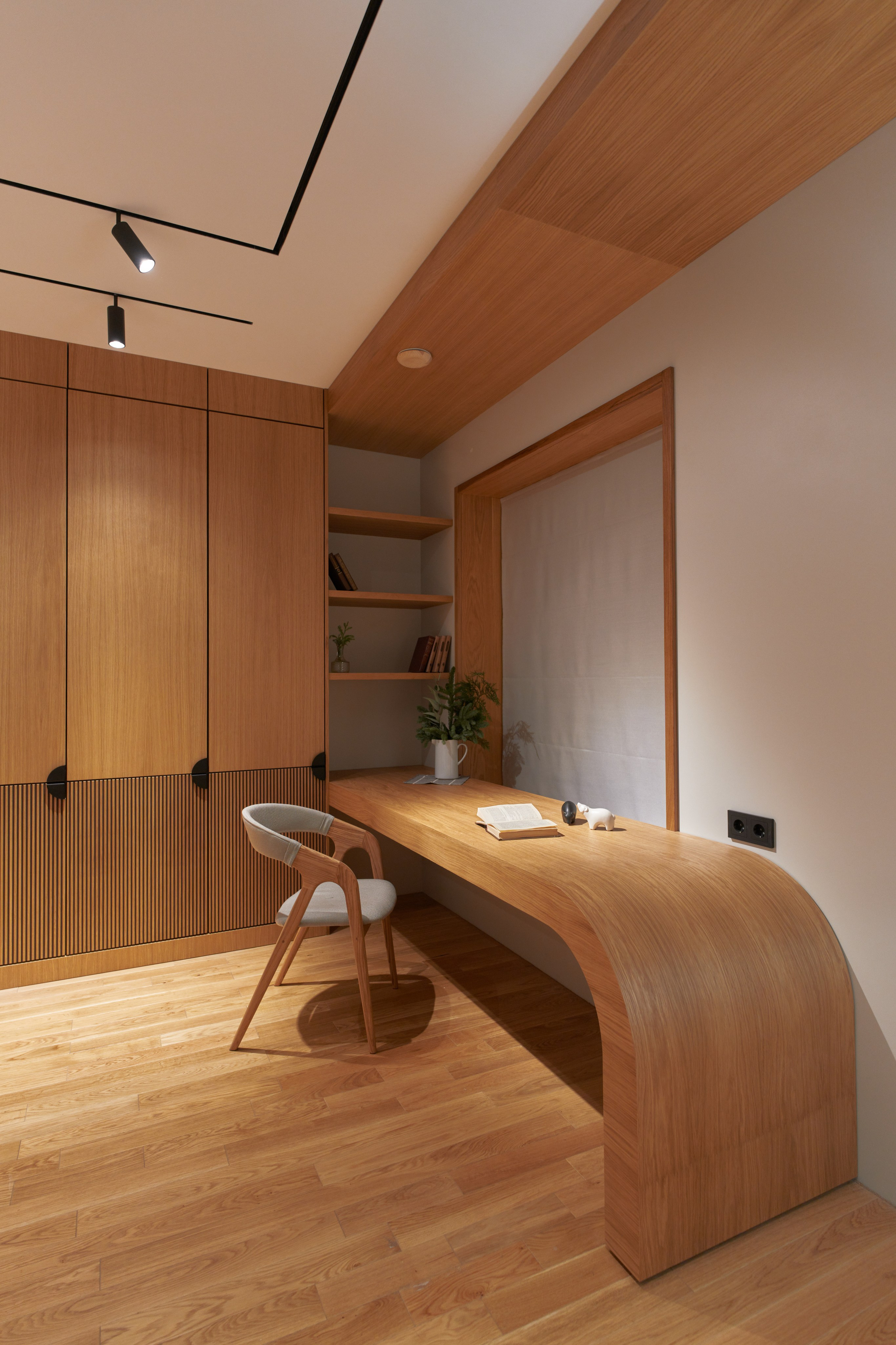 Радиусный стол с единой текстурой. Этот проект 2022 года стал для нас настоящей школой мастерства. Перед нами стояла амбициозная задача — создать стол необычной радиусной формы, где направление древесного шпона должно было оставаться единым по всем плоскостям, словно стол вырезан из цельного массива. Главный вызов: изготовить криволинейную конструкцию с идеальным совпадением текстуры дерева на горизонтальной столешнице и вертикальной опоре. Стандартные методы работы со шпоном здесь не работали — требовался особый подход. Наше решение: Мы погрузились в изучение классических столярных техник, обратившись даже к советским учебникам по столярному делу. Освоили практически забытое искусство сростки шпона по волокнам, что позволило создать бесшовное полотно с единым рисунком. Вторая сложность заключалась в самой радиусной форме — ни один промышленный пресс или вакуумный мешок не подходил для таких габаритов. Решение нашли в нестандартном подходе: разработали собственную технологию и изготовили специальные прикатные молотки вручную. Это позволило деликатно наклеить шпон на изогнутую поверхность, сохранив целостность рисунка. Результат превзошел ожидания — стол выглядит как монолитная скульптура из натурального дерева, где каждая линия текстуры перетекает с одной плоскости на другую естественно и органично.