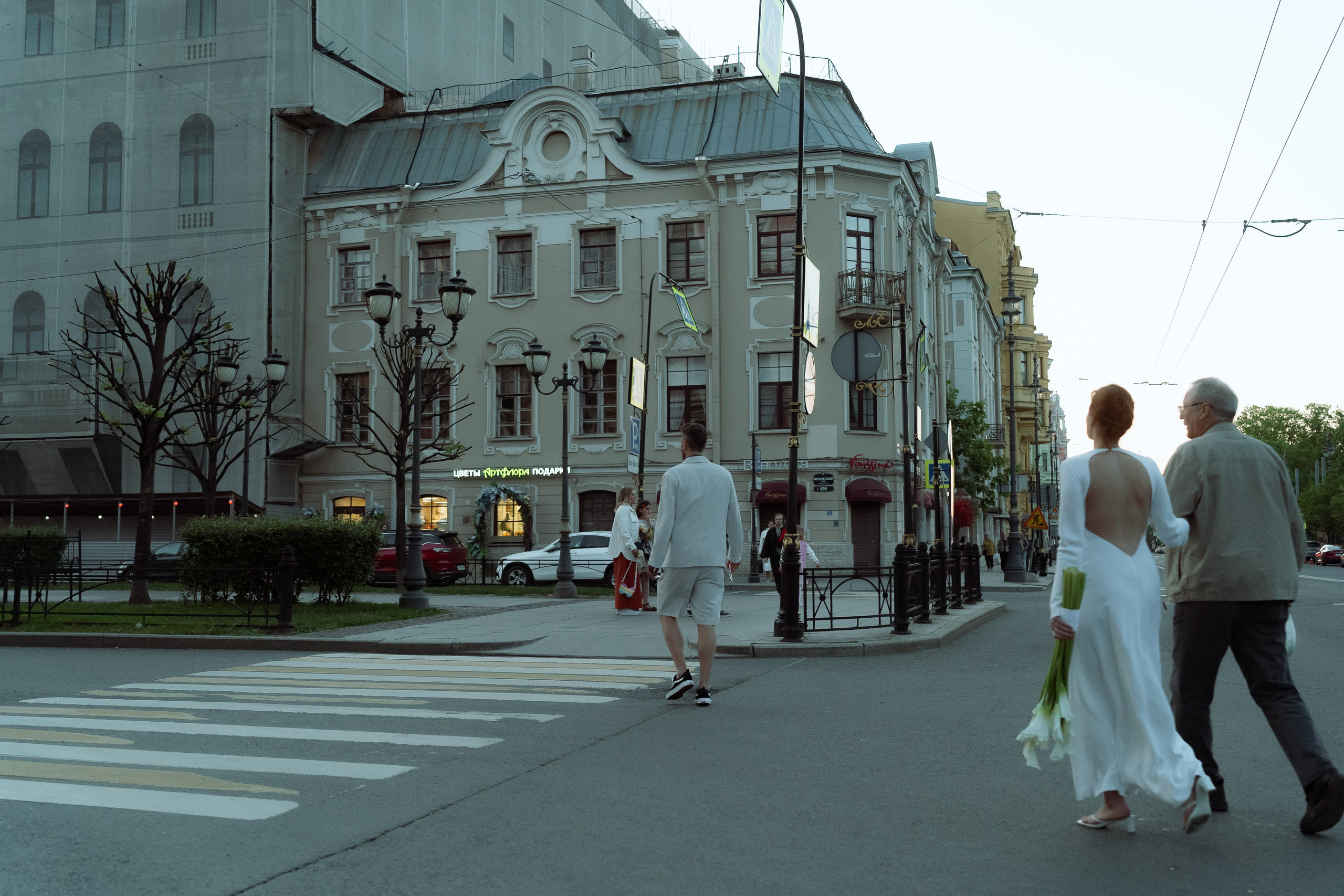 Мария и Евгений с букетом калл переходят широкую улицу Петербурга по пешеходному переходу
