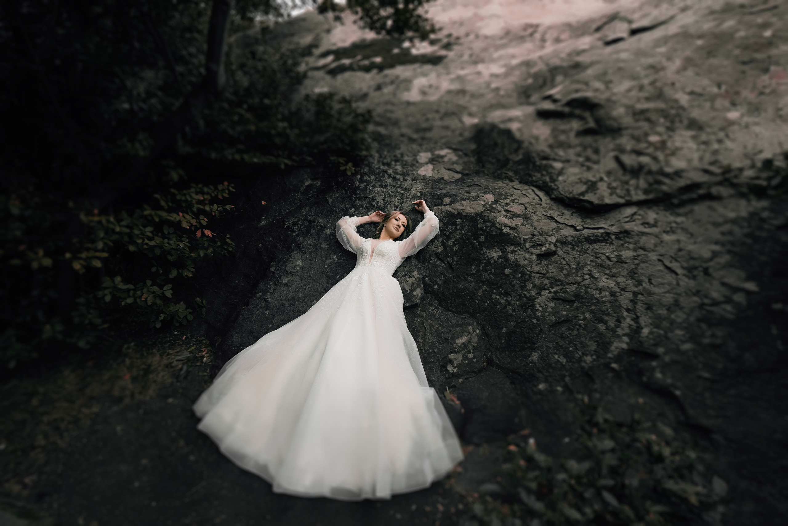 Невеста в красивом платье лежит на скале