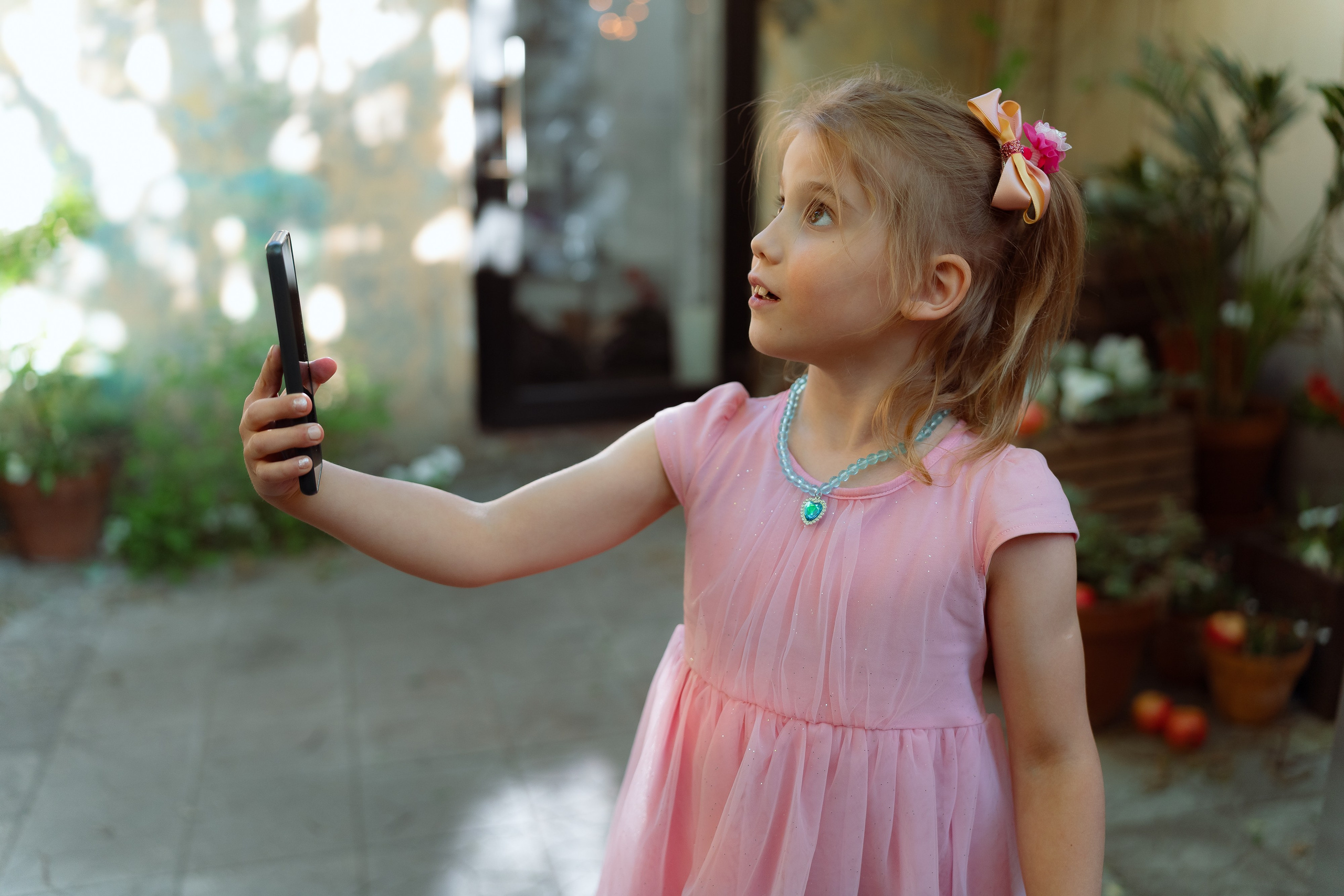 Девочка в розовой толстовке фотографируется с друзьями на террасе
