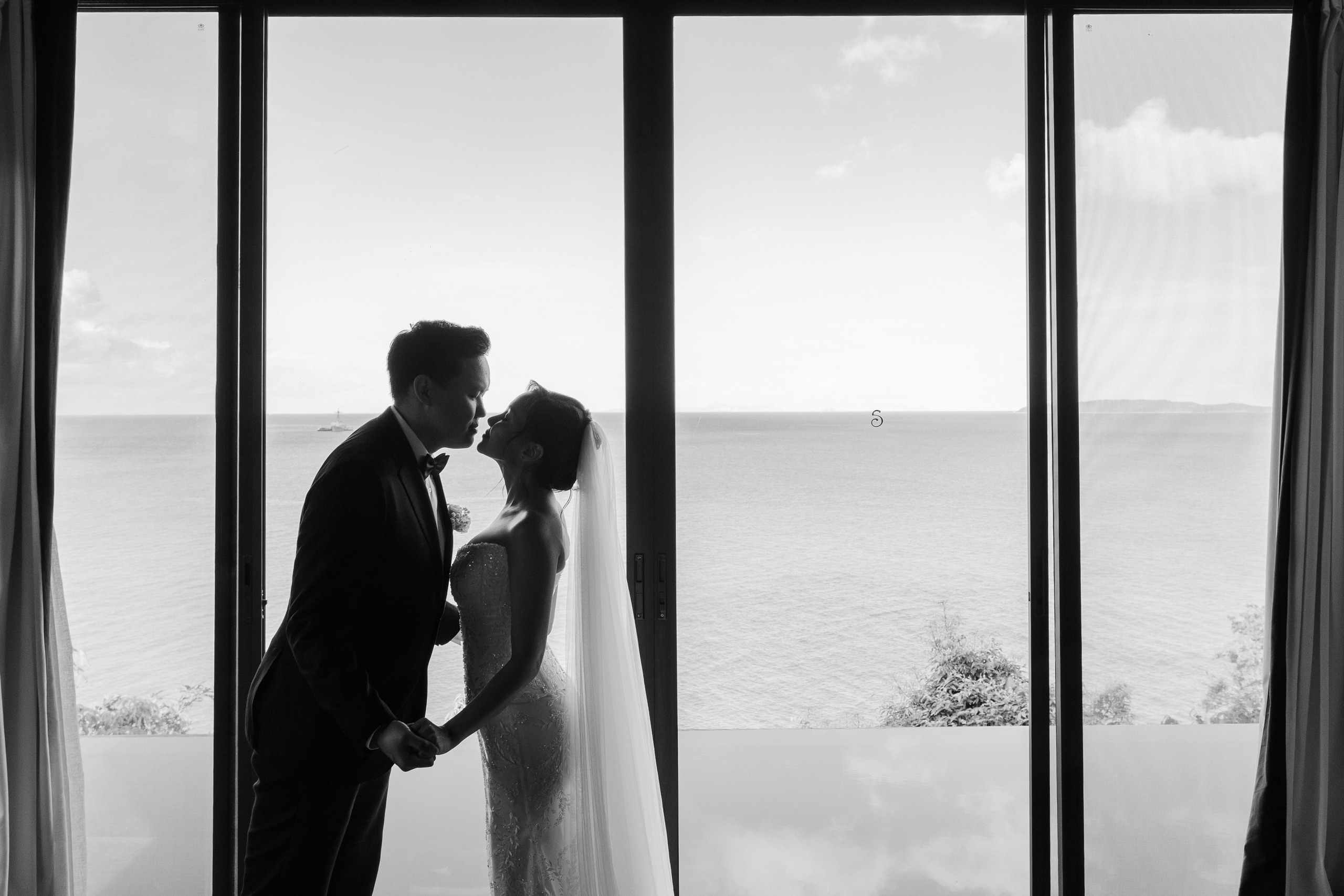 A bride and groom at a panoramic window in Phuket