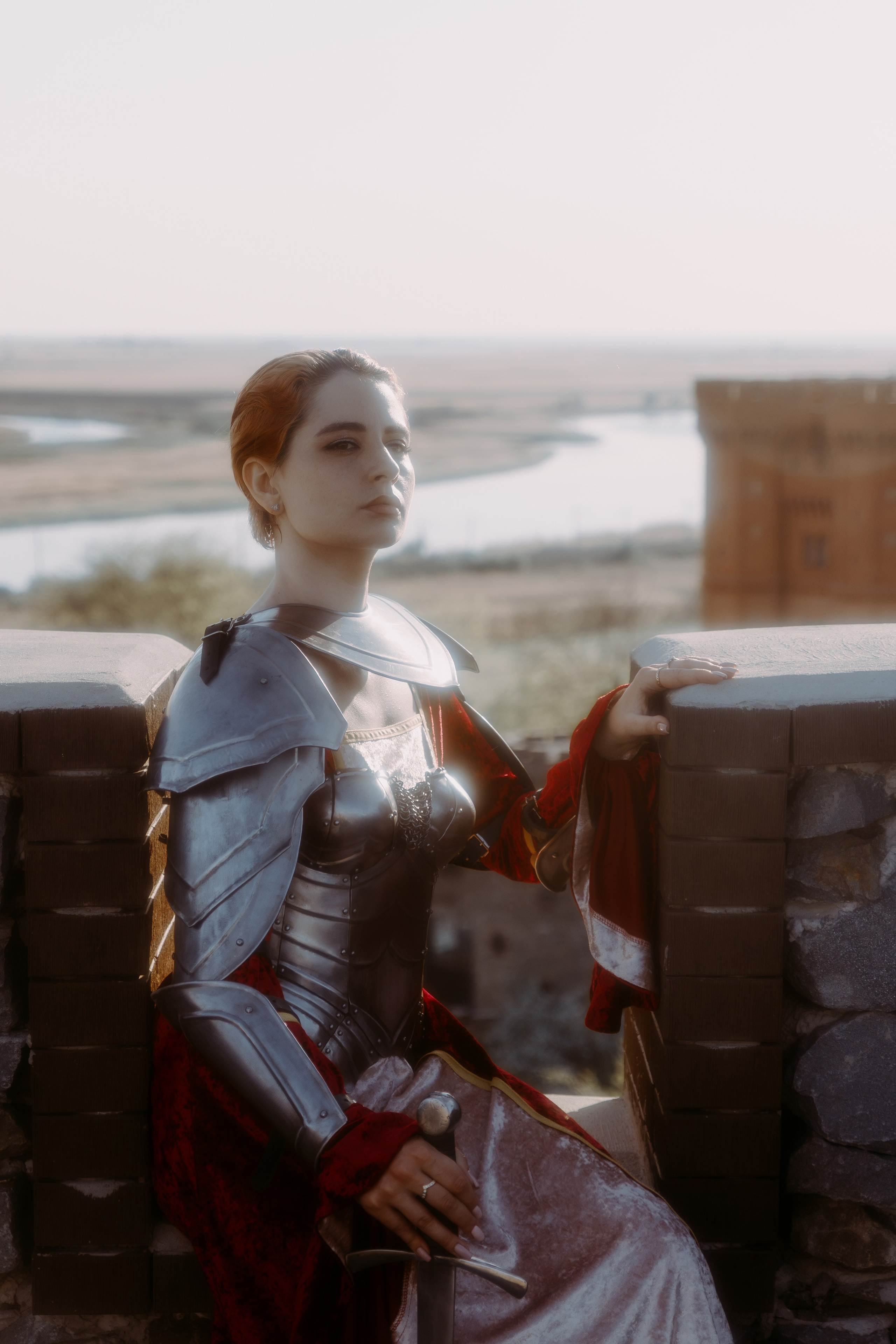 портрет девушки в рыцарских доспехах на фоне замка при закате