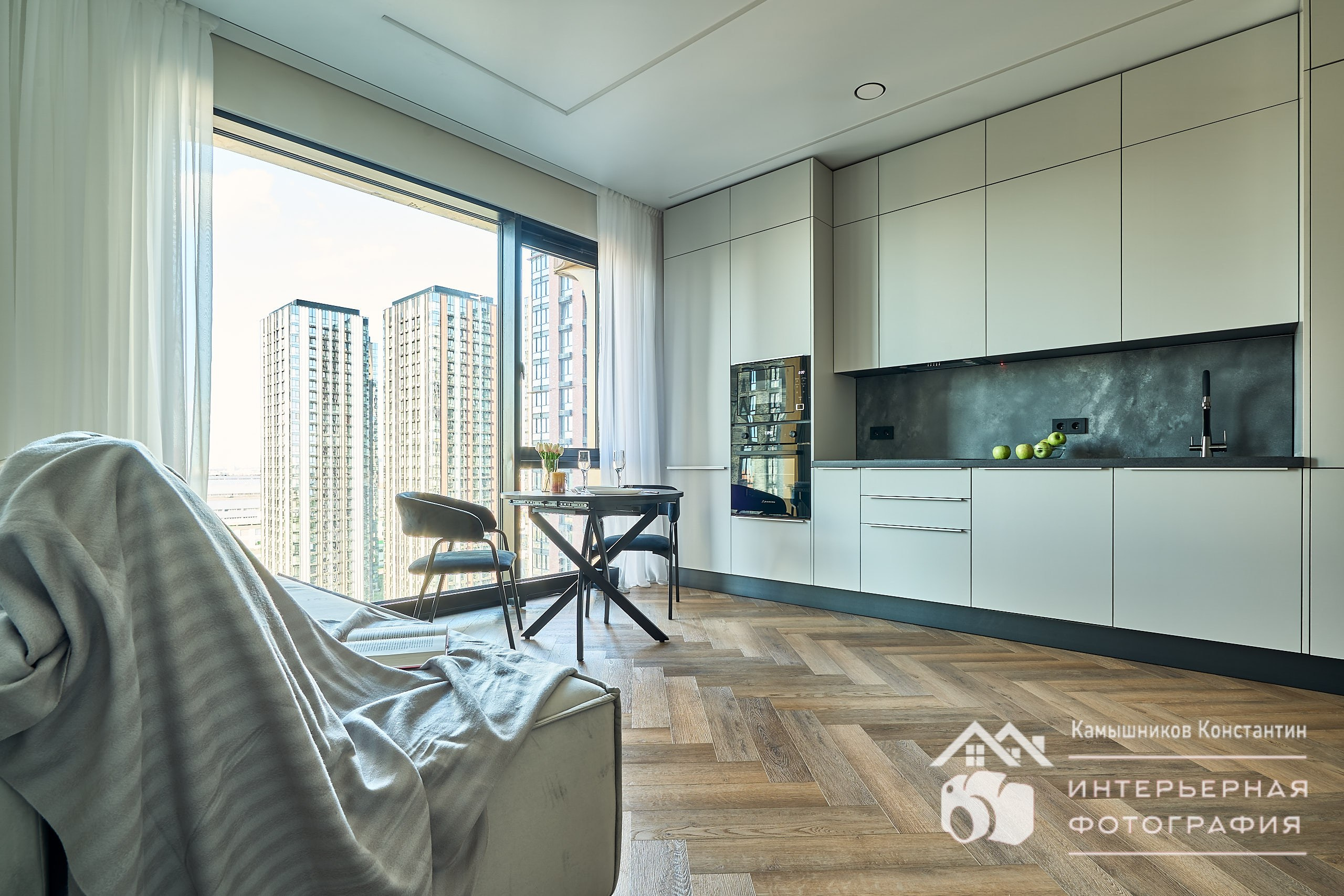 Интерьерная съемка с ракурсом на расположение кухонной зоны в гостиной жилых апартаментов в ЖК Метрополия