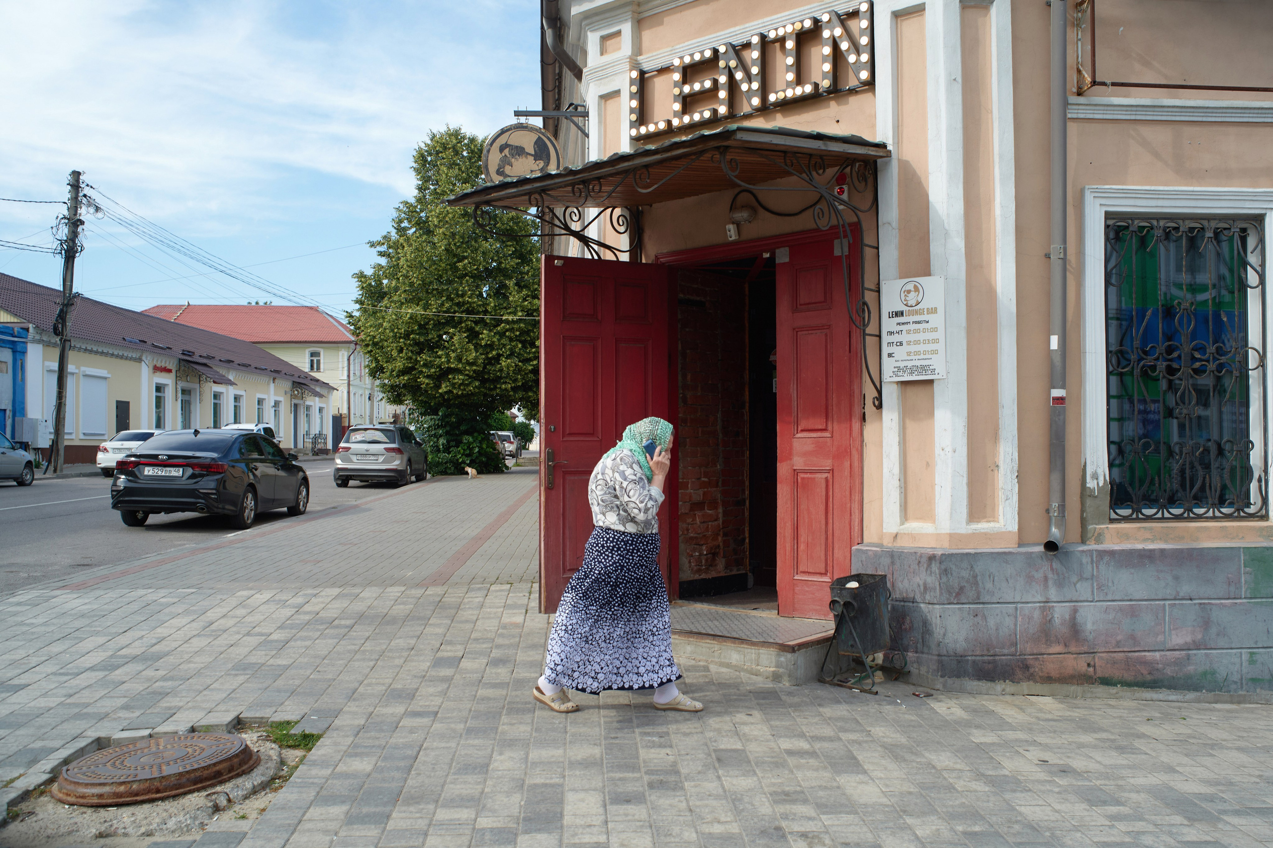 Женщина идет из православного собора мимо бара Lenin в Ельце, Липецкая область
