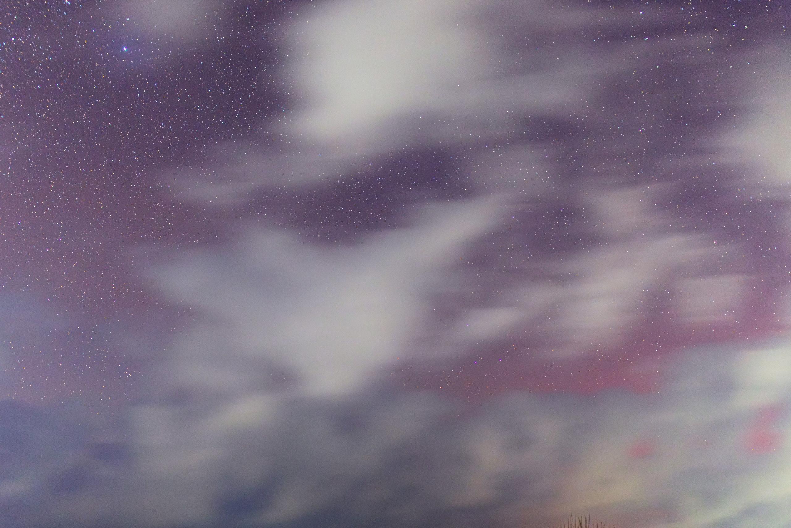 Красивое алое сияние на звёздном небе с белыми тучами