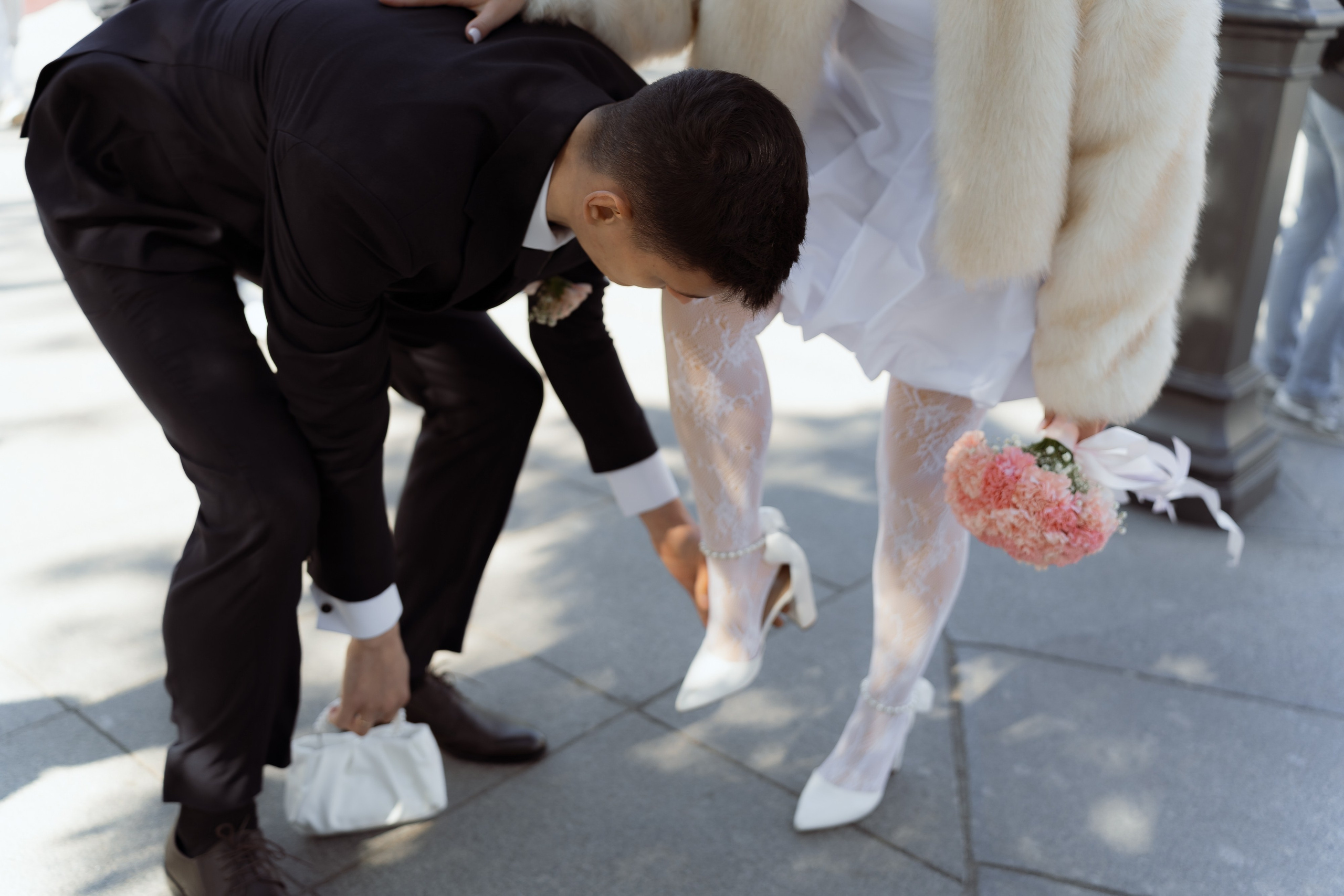 Жених помогает невесте с обувью, заботливый момент на прогулке