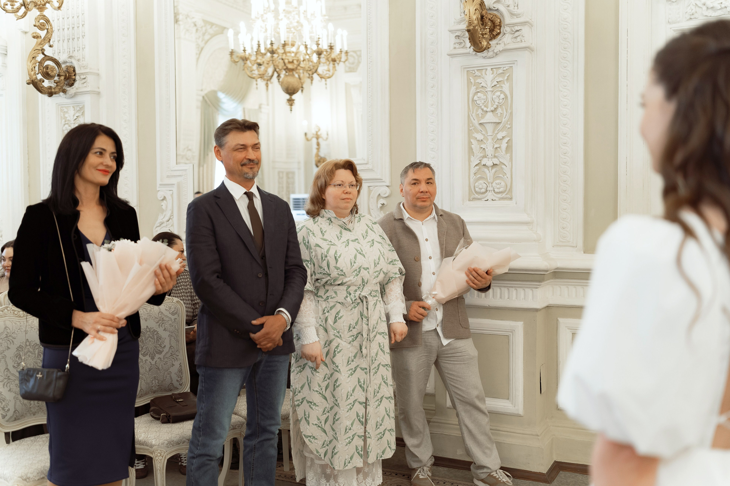 Гости и родственники поздравляют молодожёнов в зале дворца бракосочетания