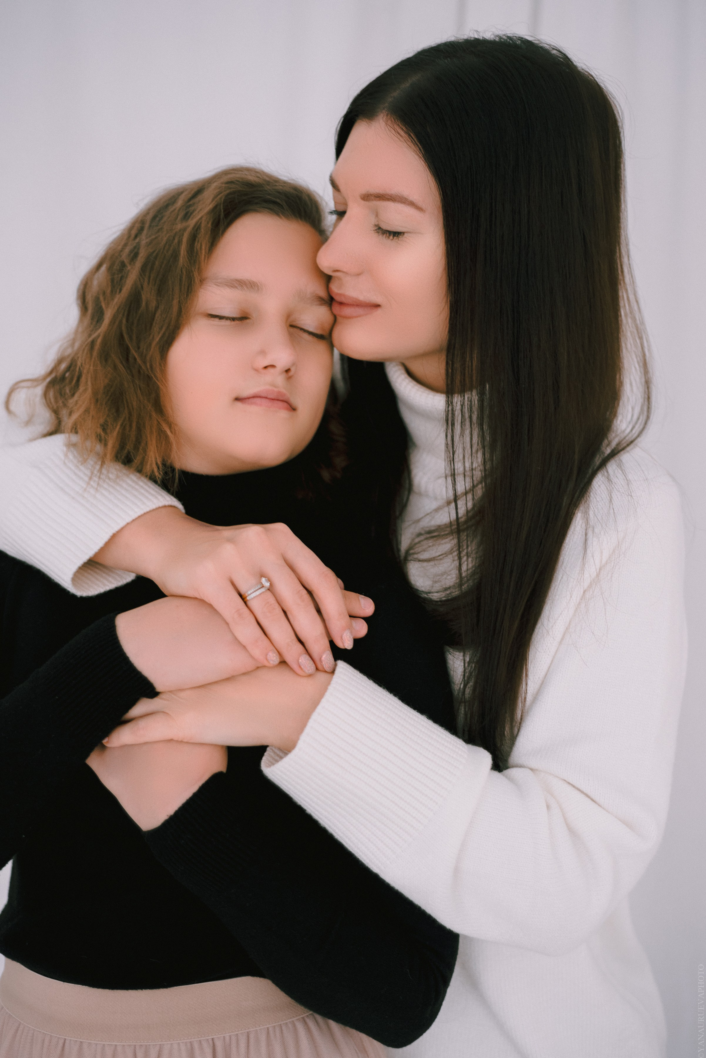 Мама обнимает дочь на белом фоне